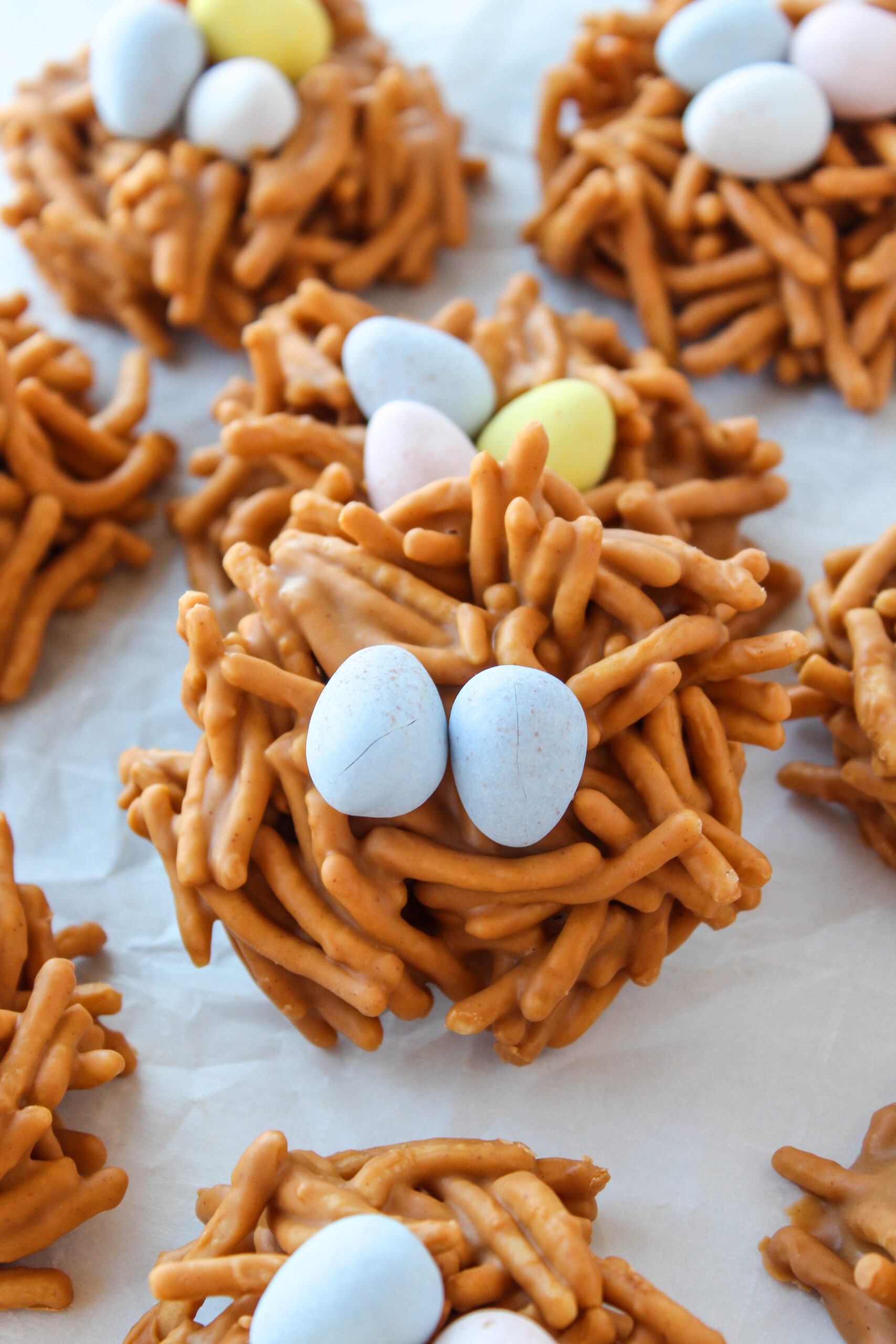 Close‑up of butterscotch peanut butter bird nest cookies with a crunchy texture and candy eggs in the center.