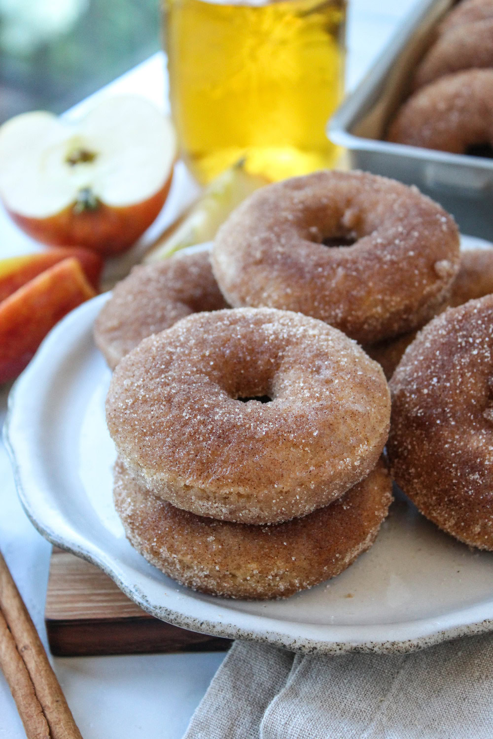 Freshly baked apple cider donuts with a cinnamon-sugar coating arranged on a serving platter