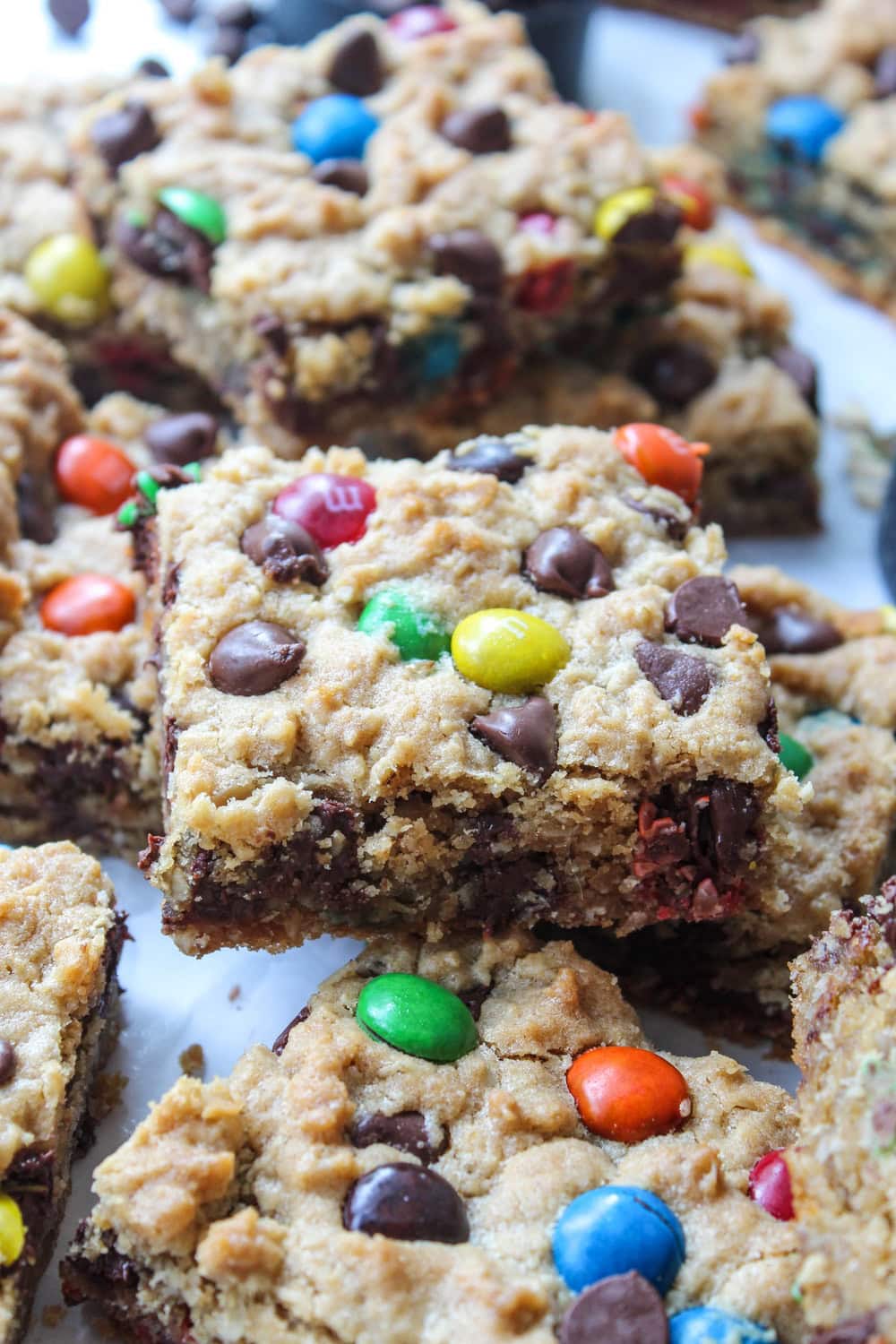 Monster cookie bars on parchment paper with a thick, soft texture and crunchy edges