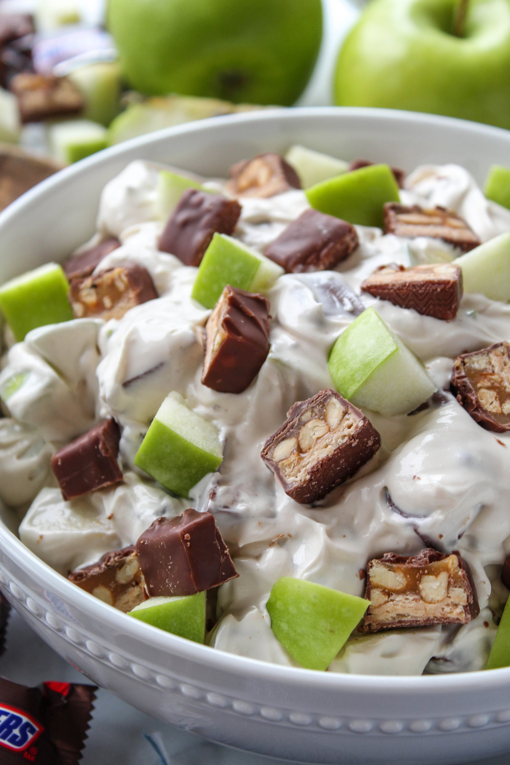 Close-up of creamy Snickers apple salad with diced apples and Snickers pieces in fluffy dressing