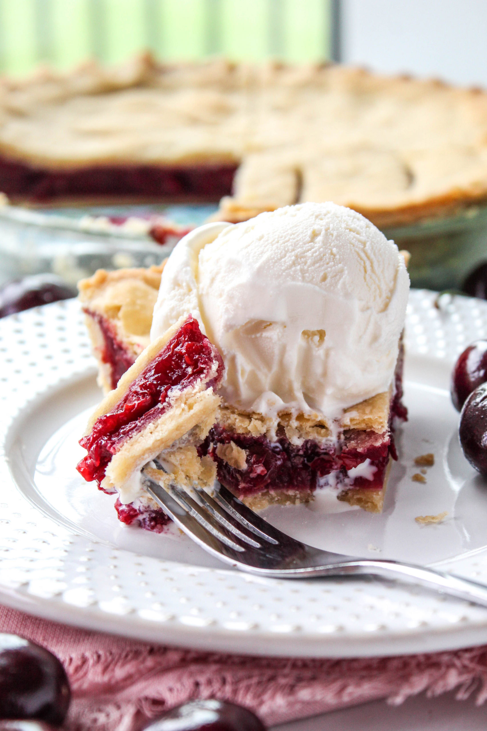 Homemade cherry pie served with flaky crust, glossy cherry filling, and ice cream