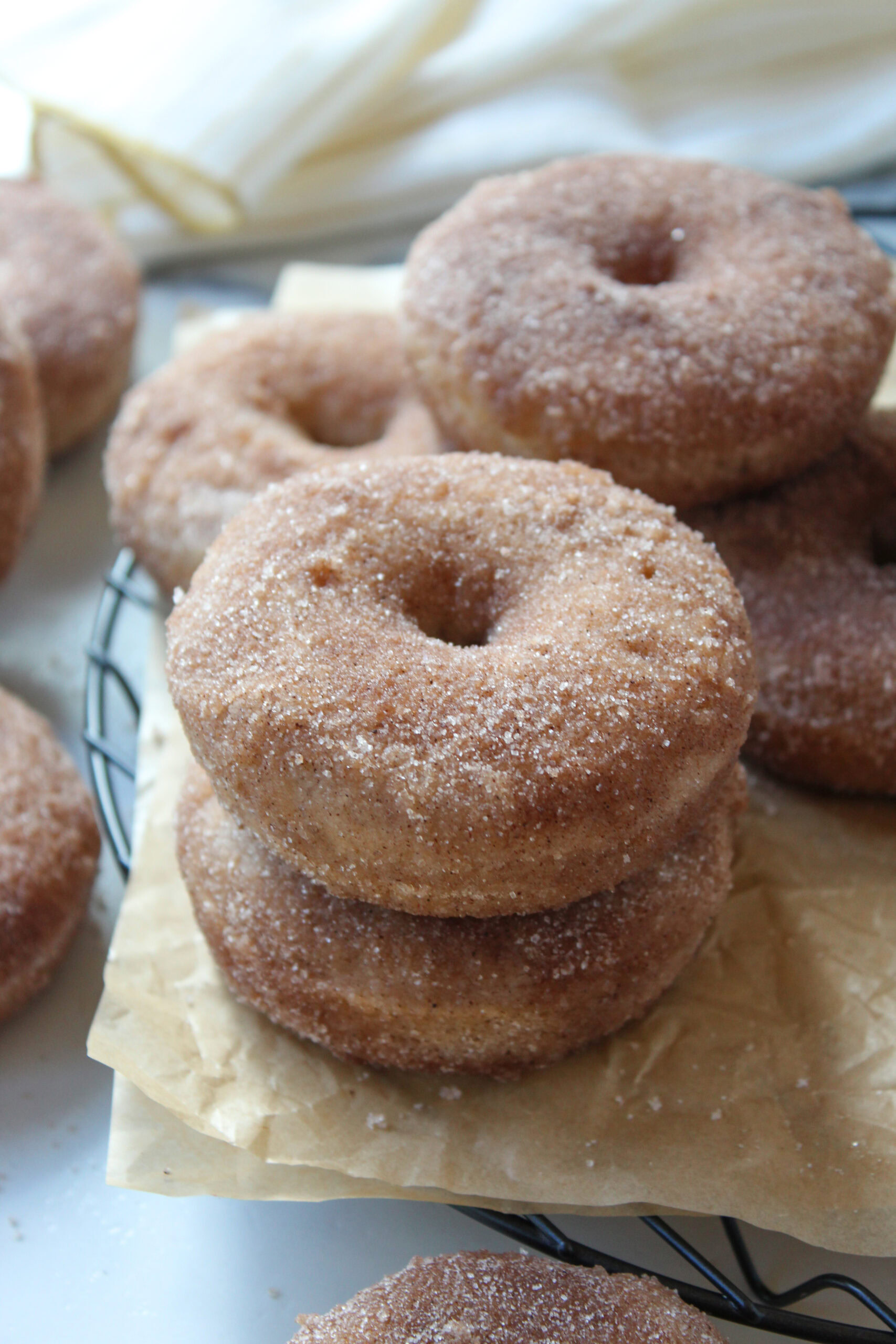 Warm baked cinnamon sugar donuts stacked on a cooling rack