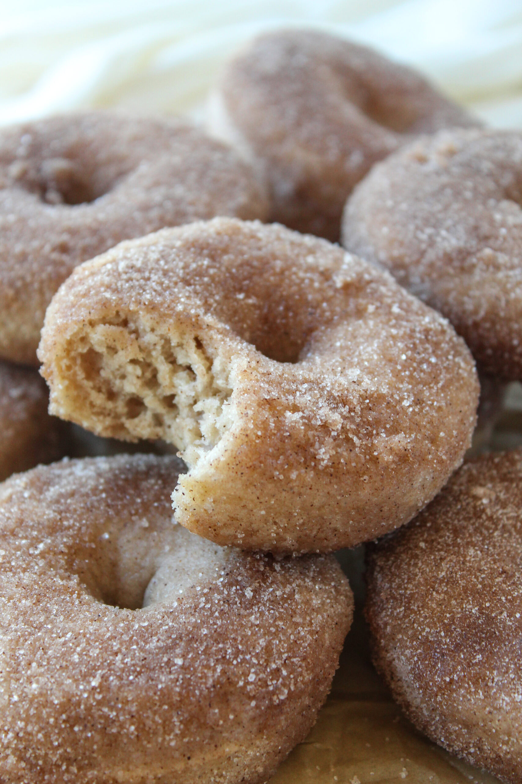 Golden baked donuts covered in cinnamon sugar on a parchment‑lined tray.