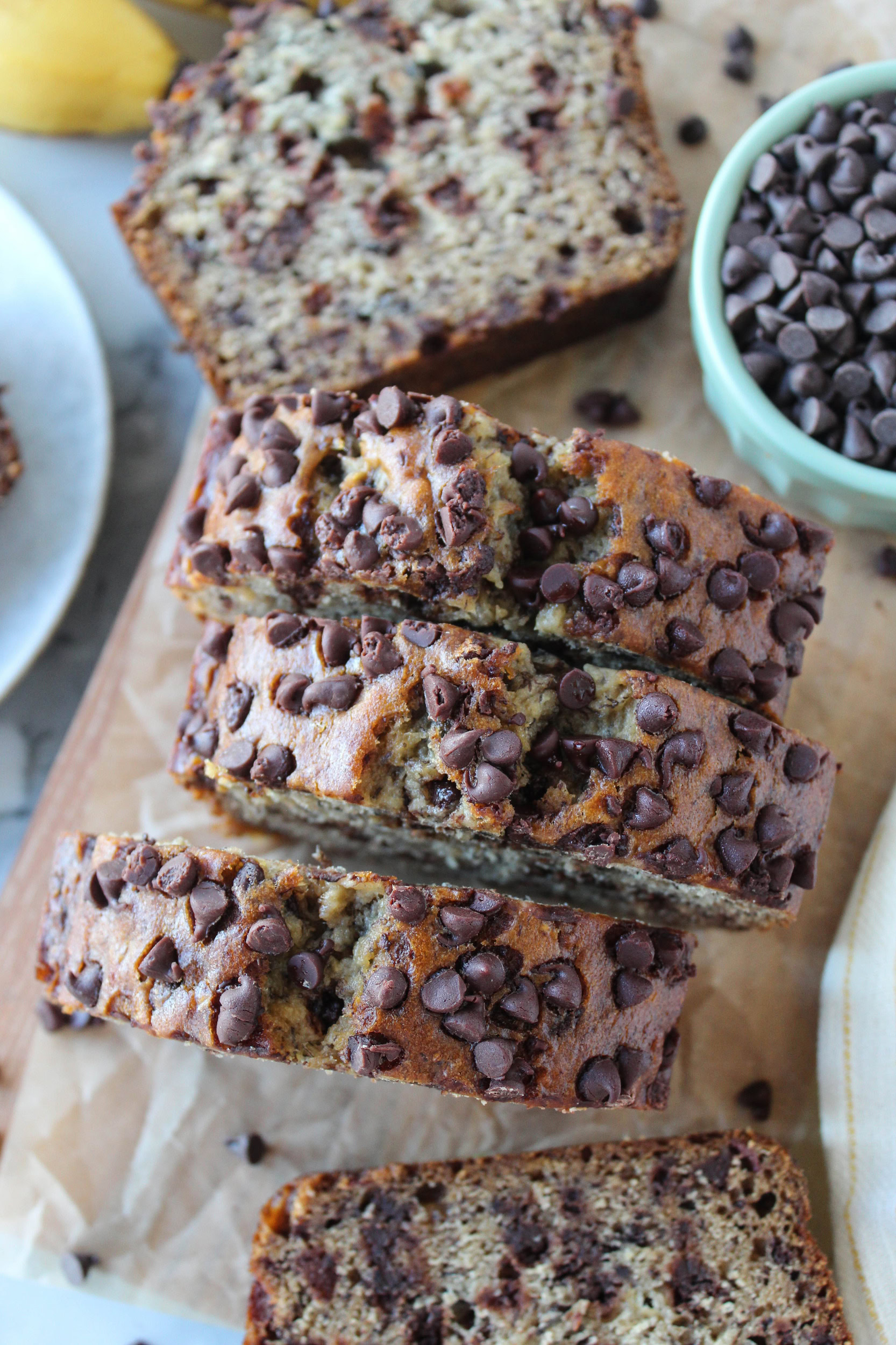 Moist chocolate chip banana bread sliced and served on a wooden cutting board