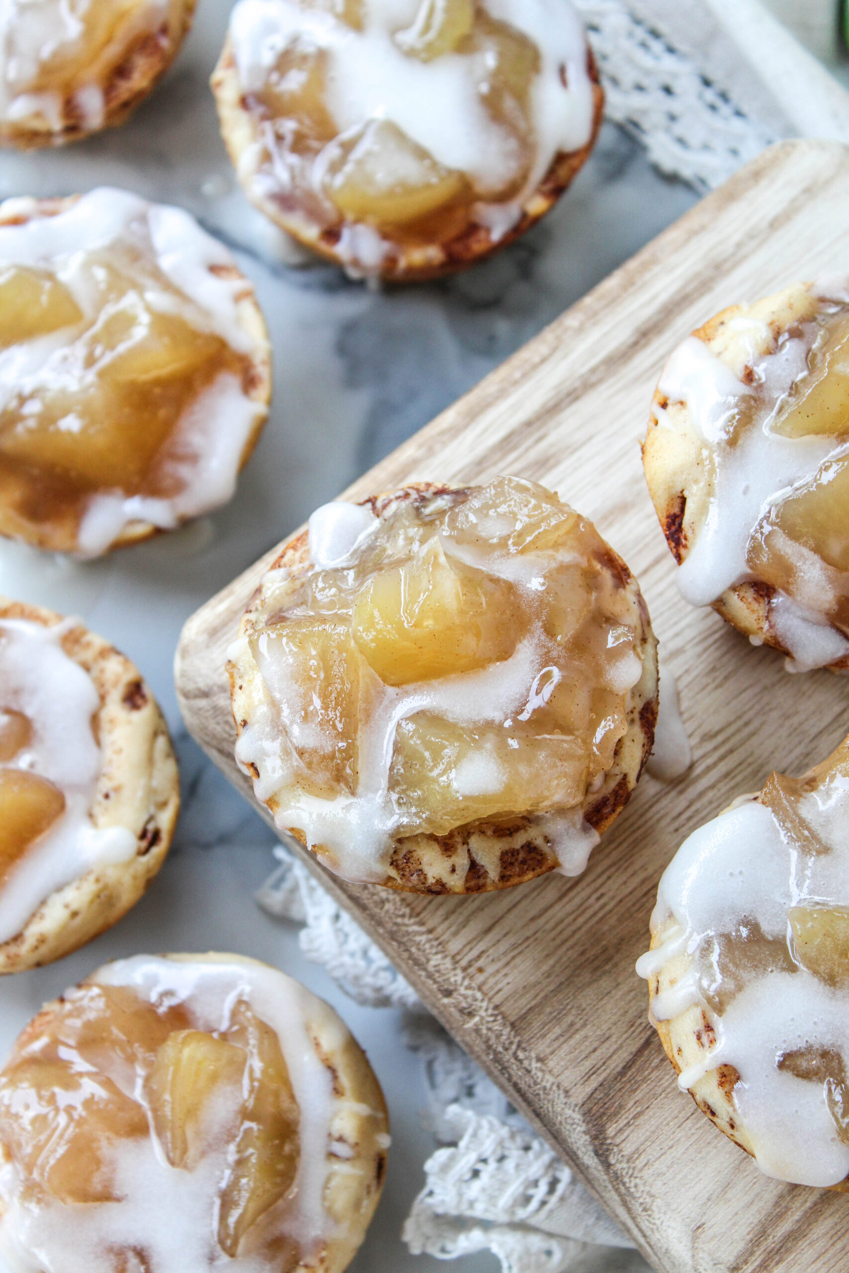 Apple pie cinnamon roll cups arranged on a wooden board