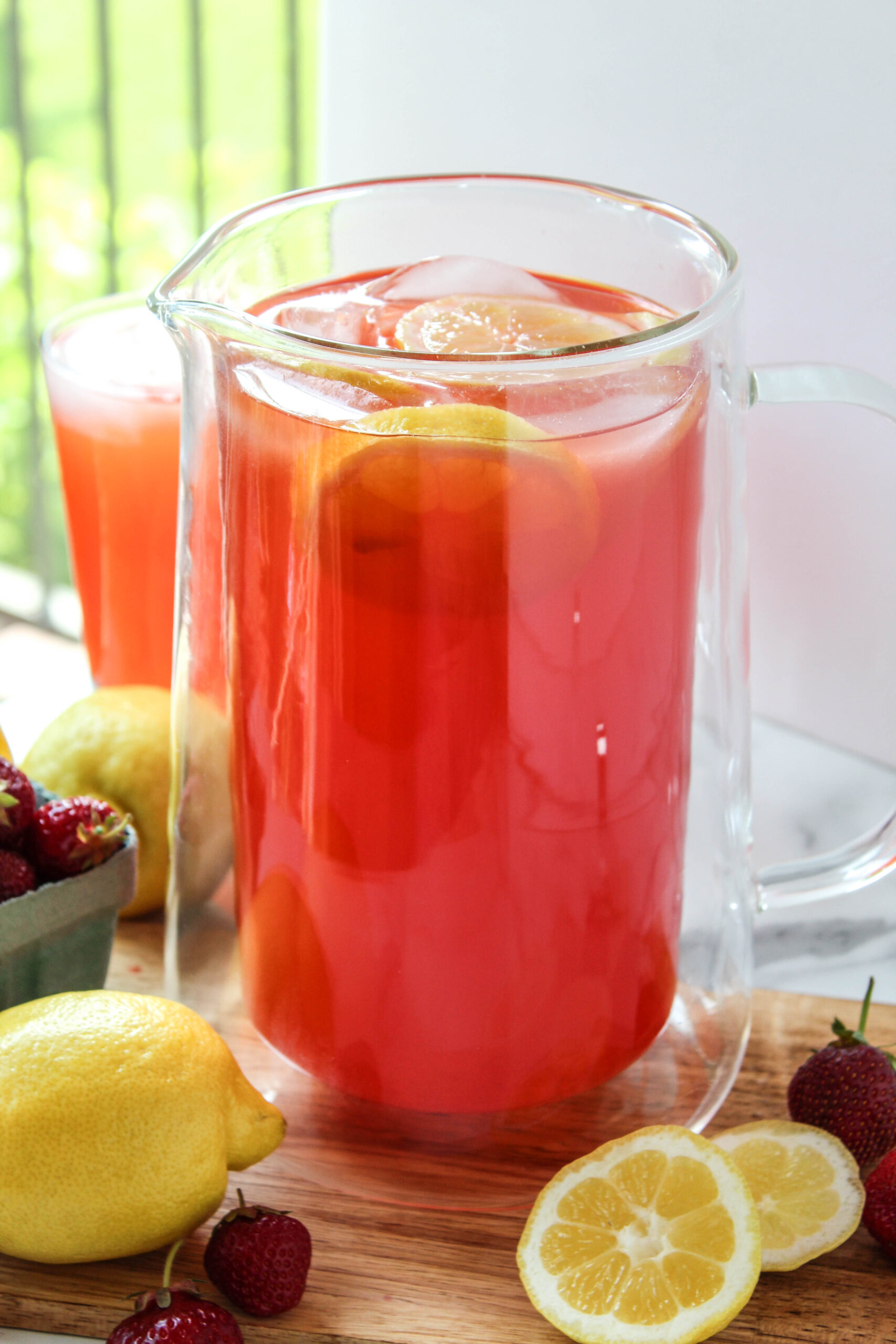 homemade strawberry lemonade in glass pitcher with fresh strawberries