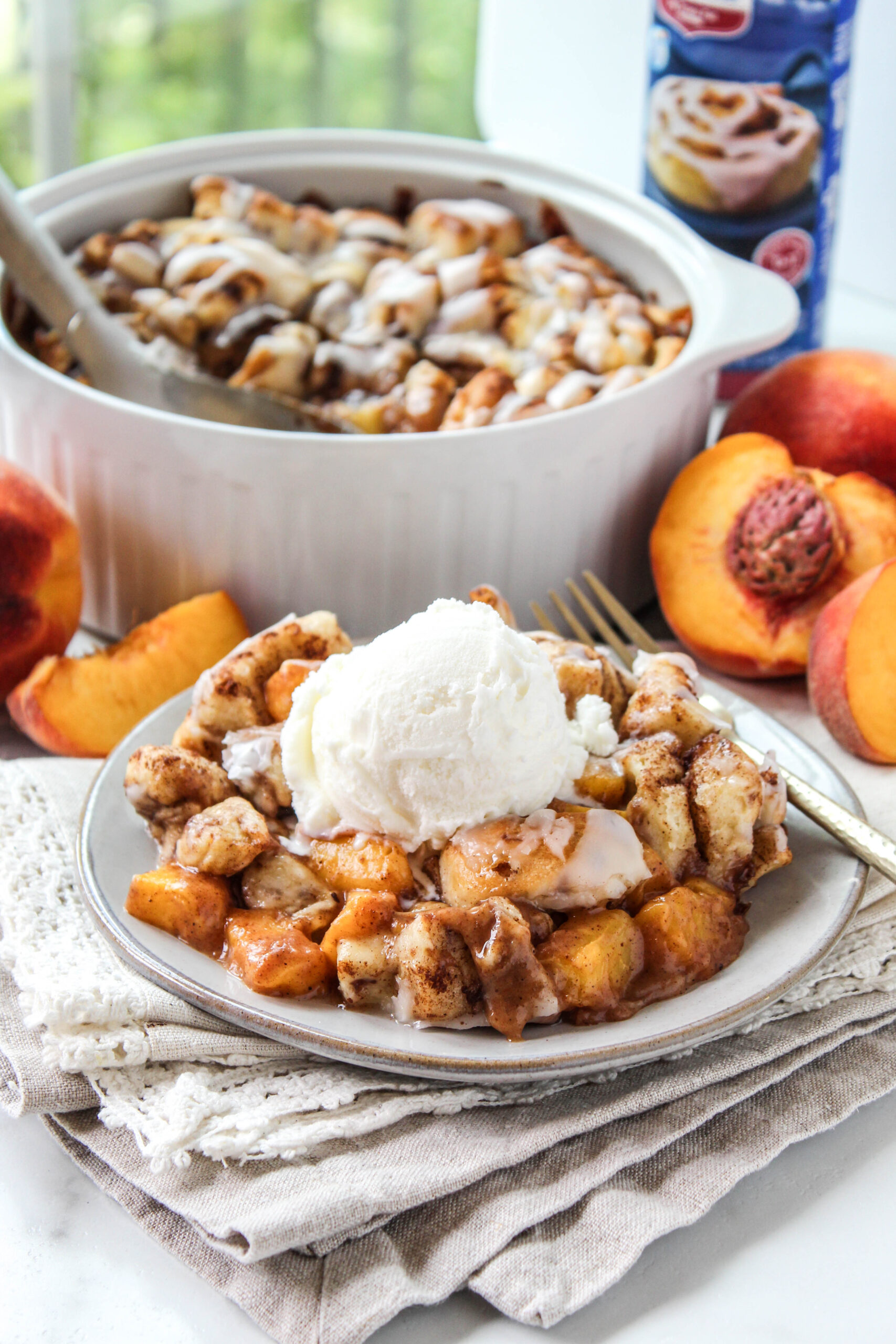 Homemade cinnamon roll peach cobbler with golden cinnamon roll topping