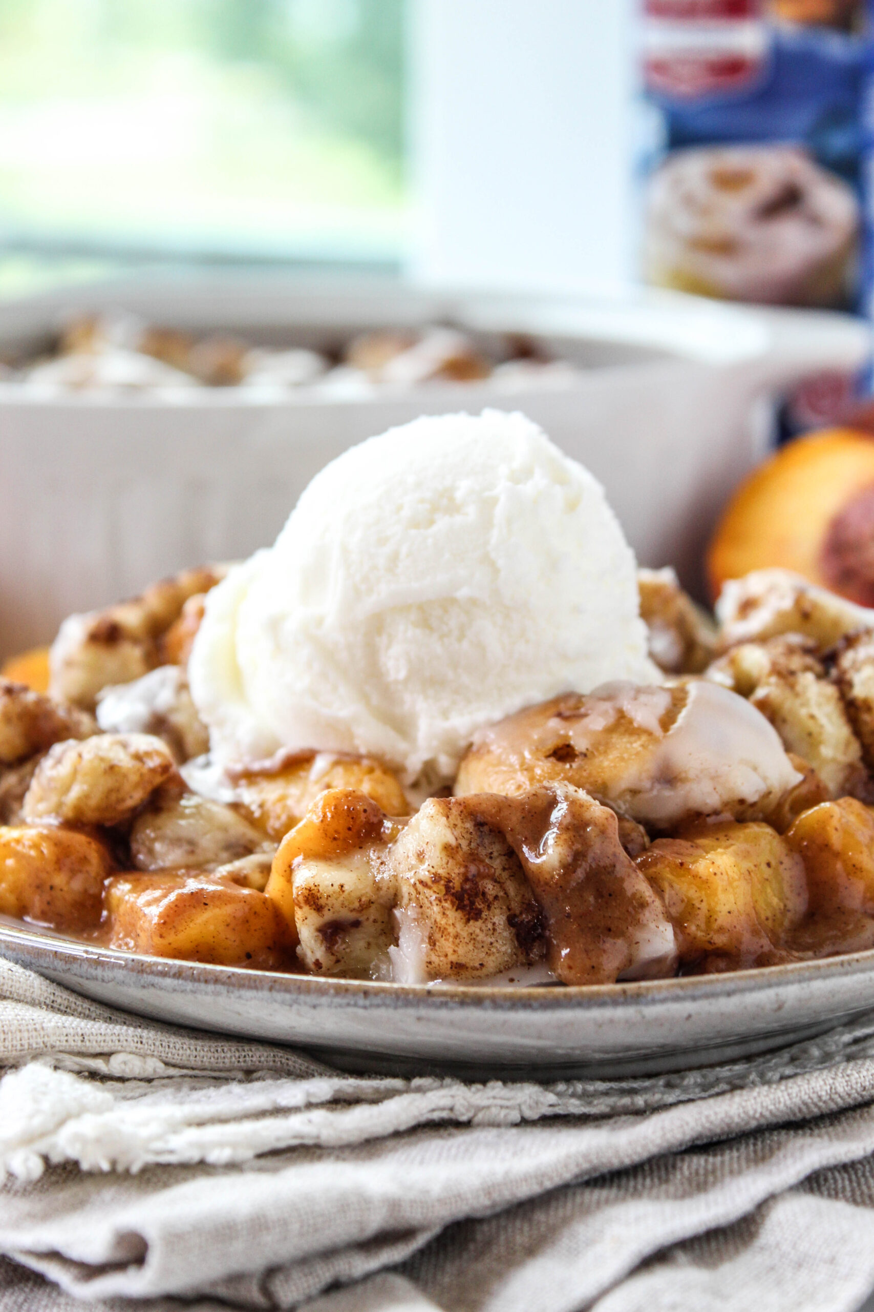 Freshly baked cinnamon roll peach cobbler with juicy peaches and gooey cinnamon rolls