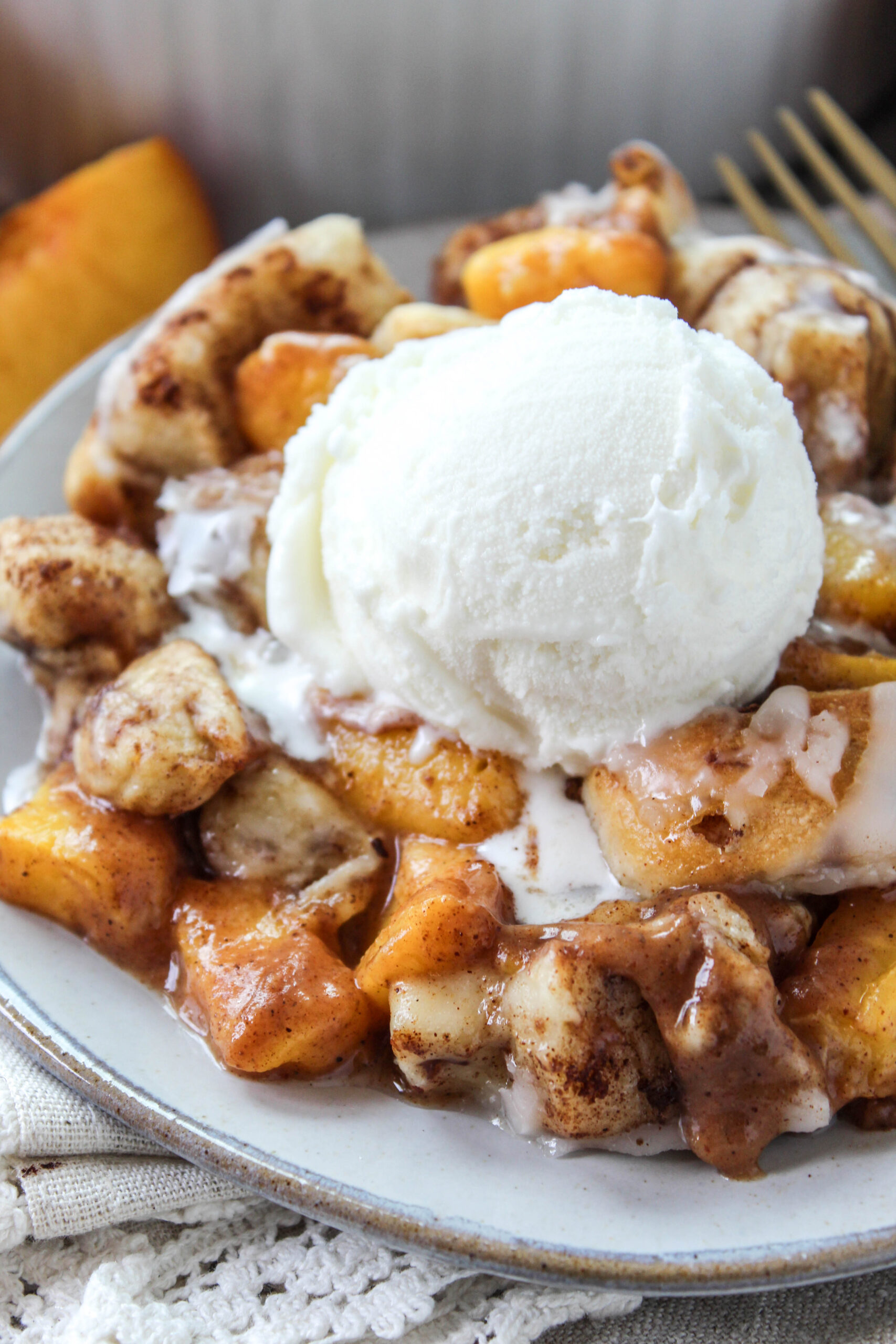 Close-up of cinnamon roll peach cobbler with soft peaches and sweet glaze