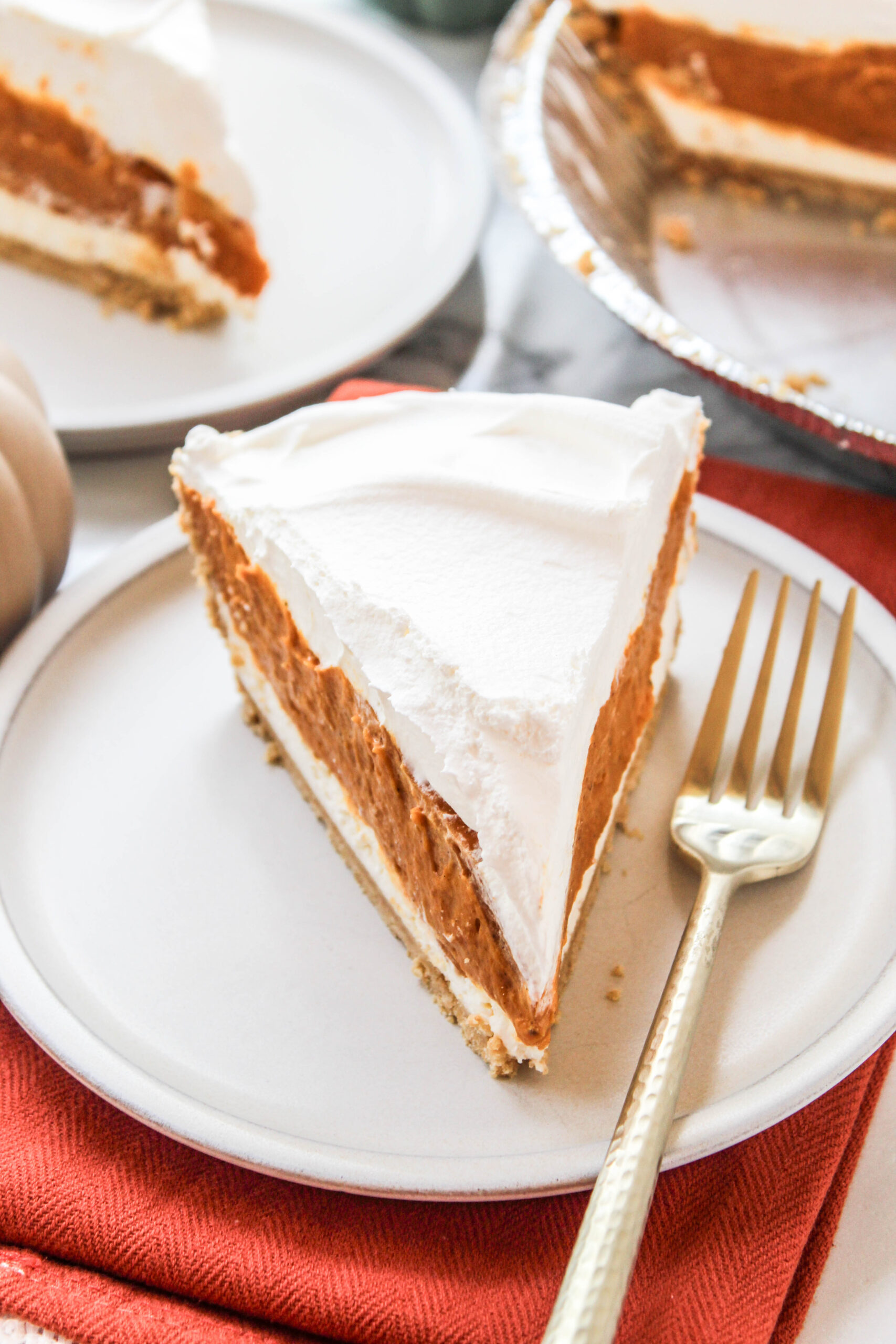 No-bake triple layer pumpkin pie topped with whipped cream and pumpkin spice
