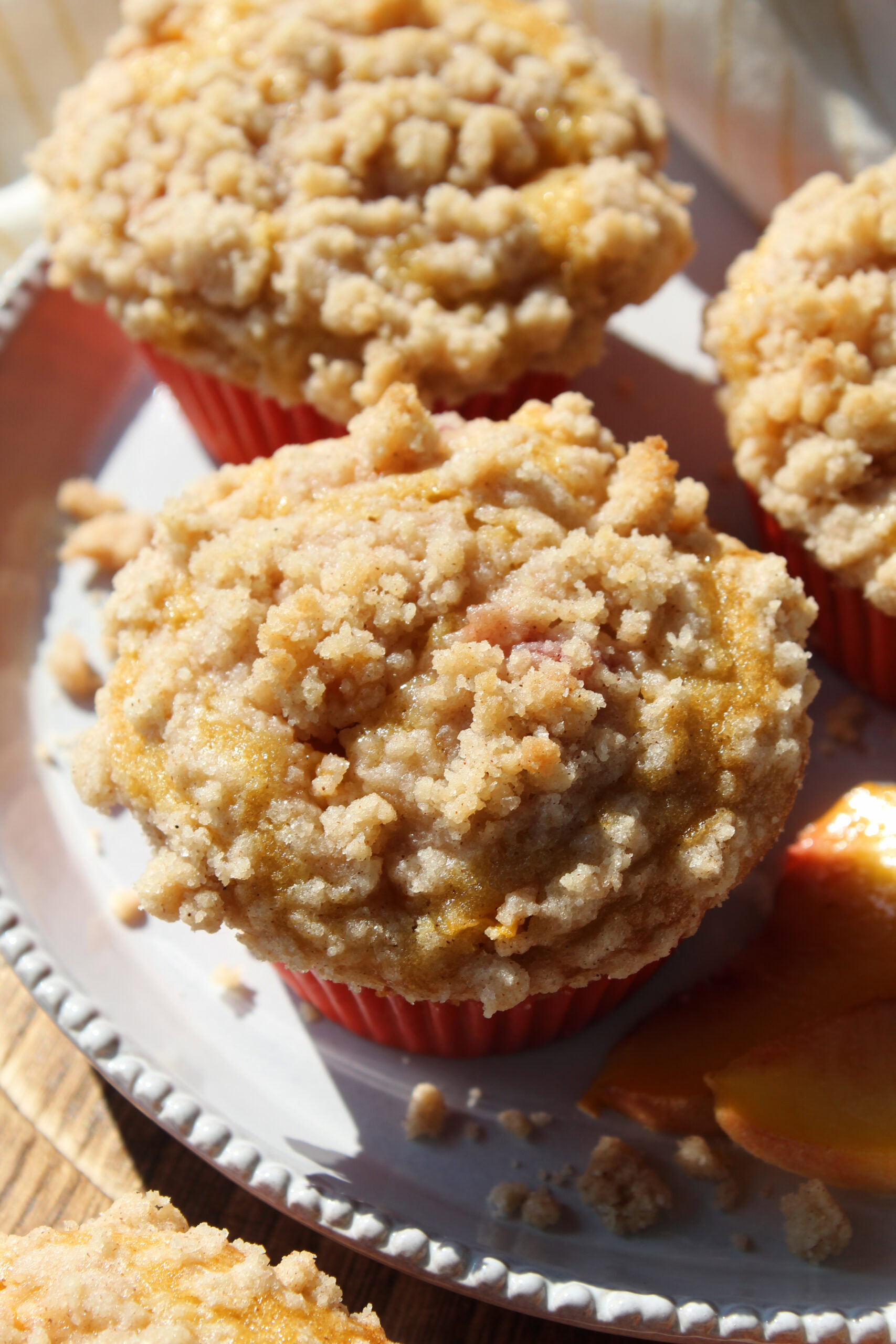 Close-up of peach cobbler muffins with soft centers and crisp, sugary crumble