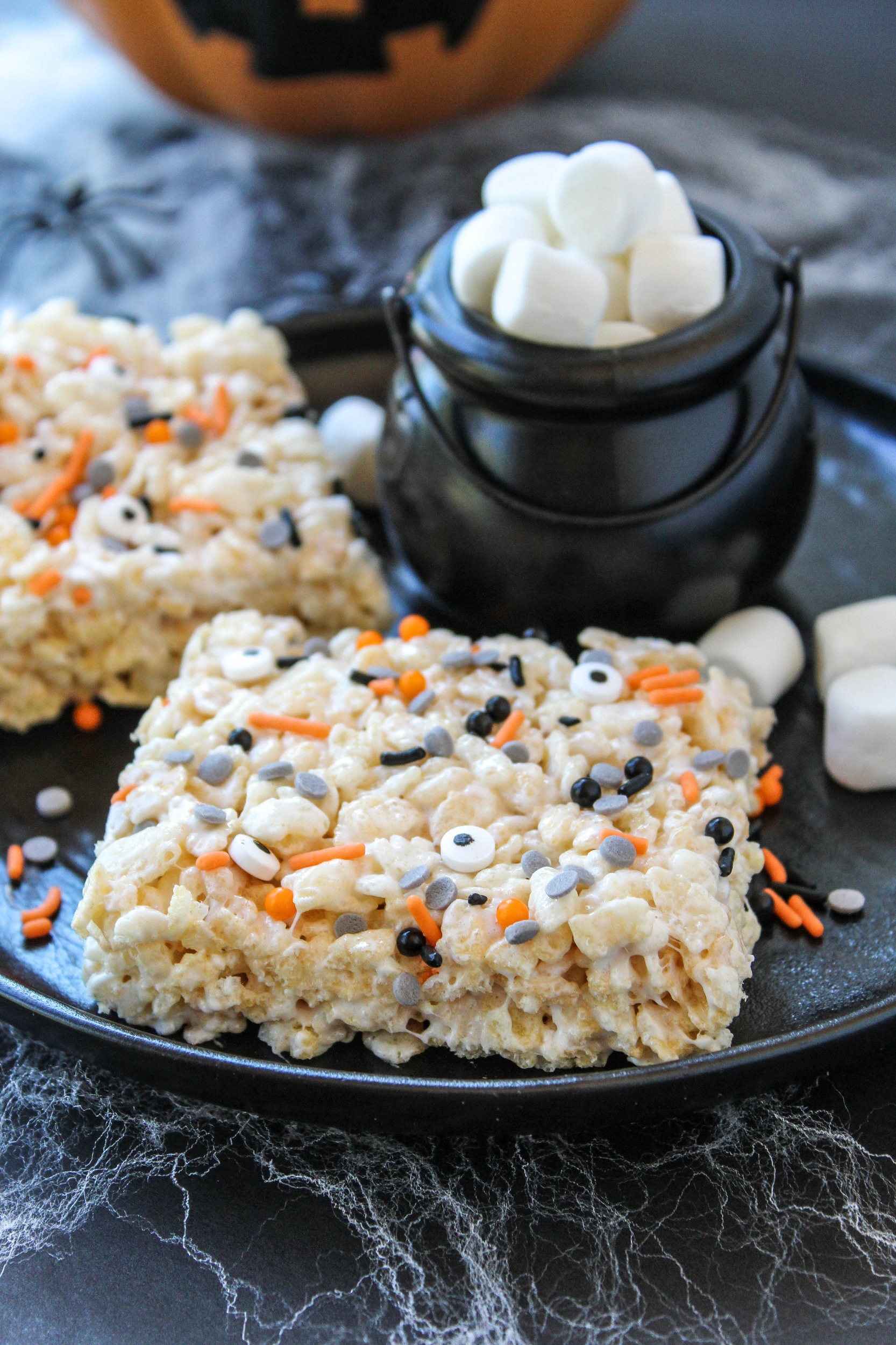 Homemade Rice Krispie treats arranged on a platter with spooky Halloween decorations