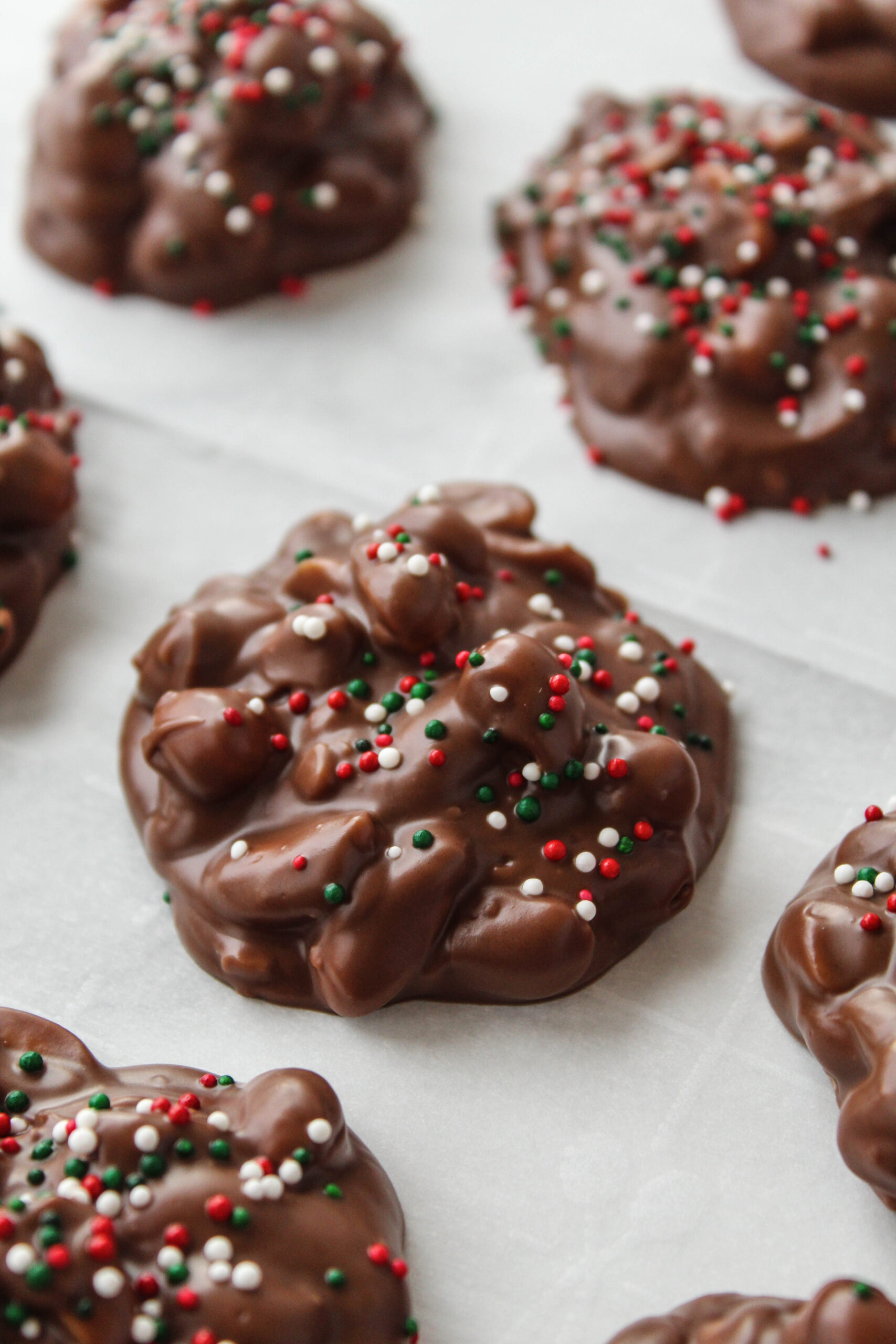 Crock Pot Christmas Crack candy clusters made with chocolate, peanuts, and festive sprinkles