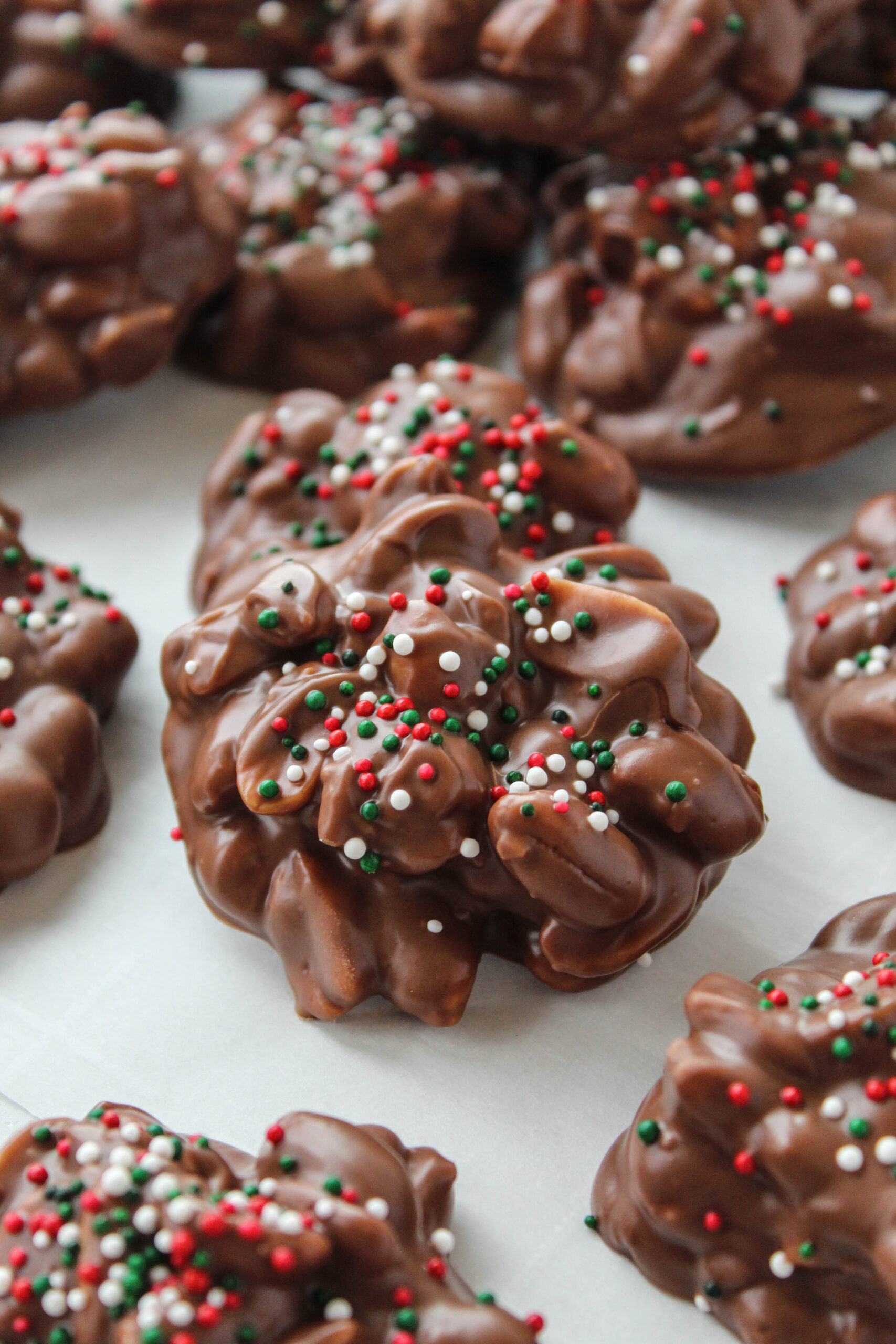 Slow cooker Christmas crack candy with chocolate, peanuts, and holiday sprinkles