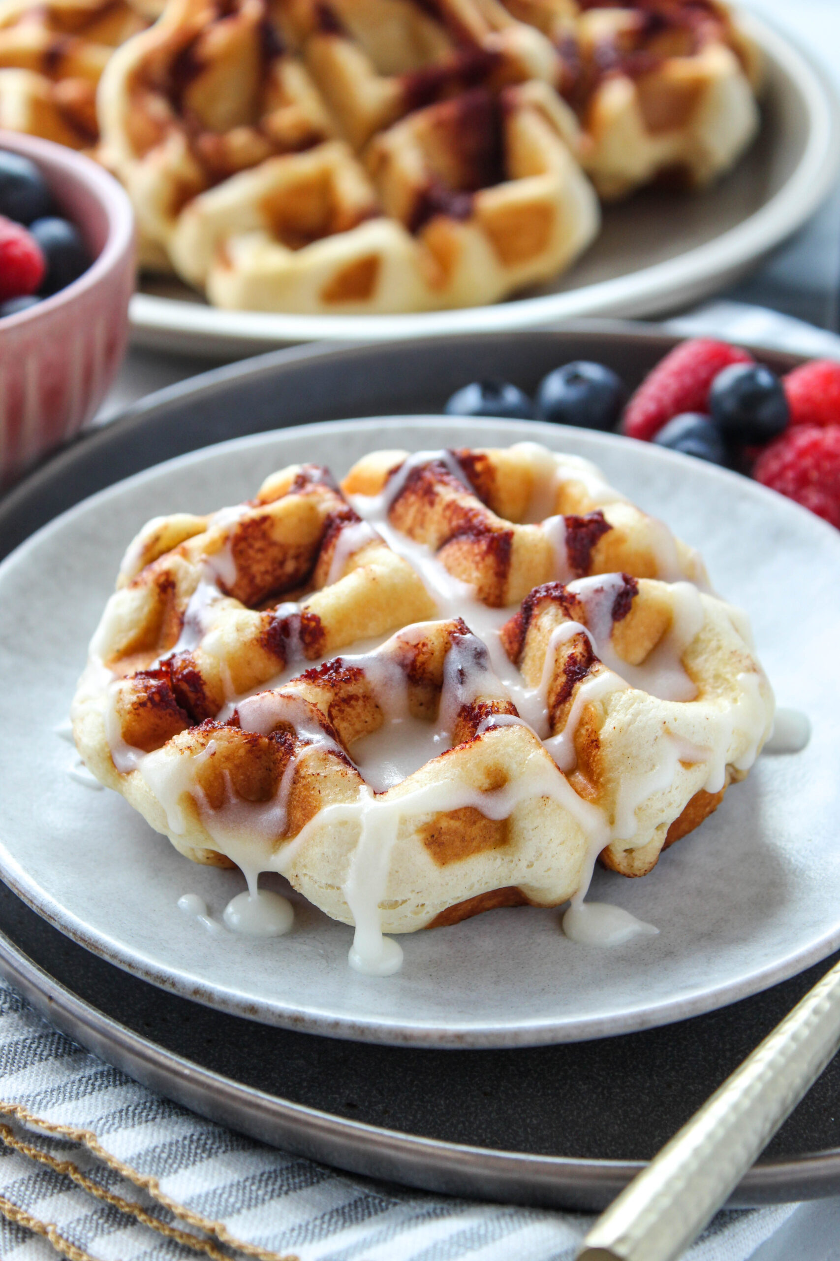 Easy cinnamon roll waffles drizzled with sweet icing on a breakfast plate