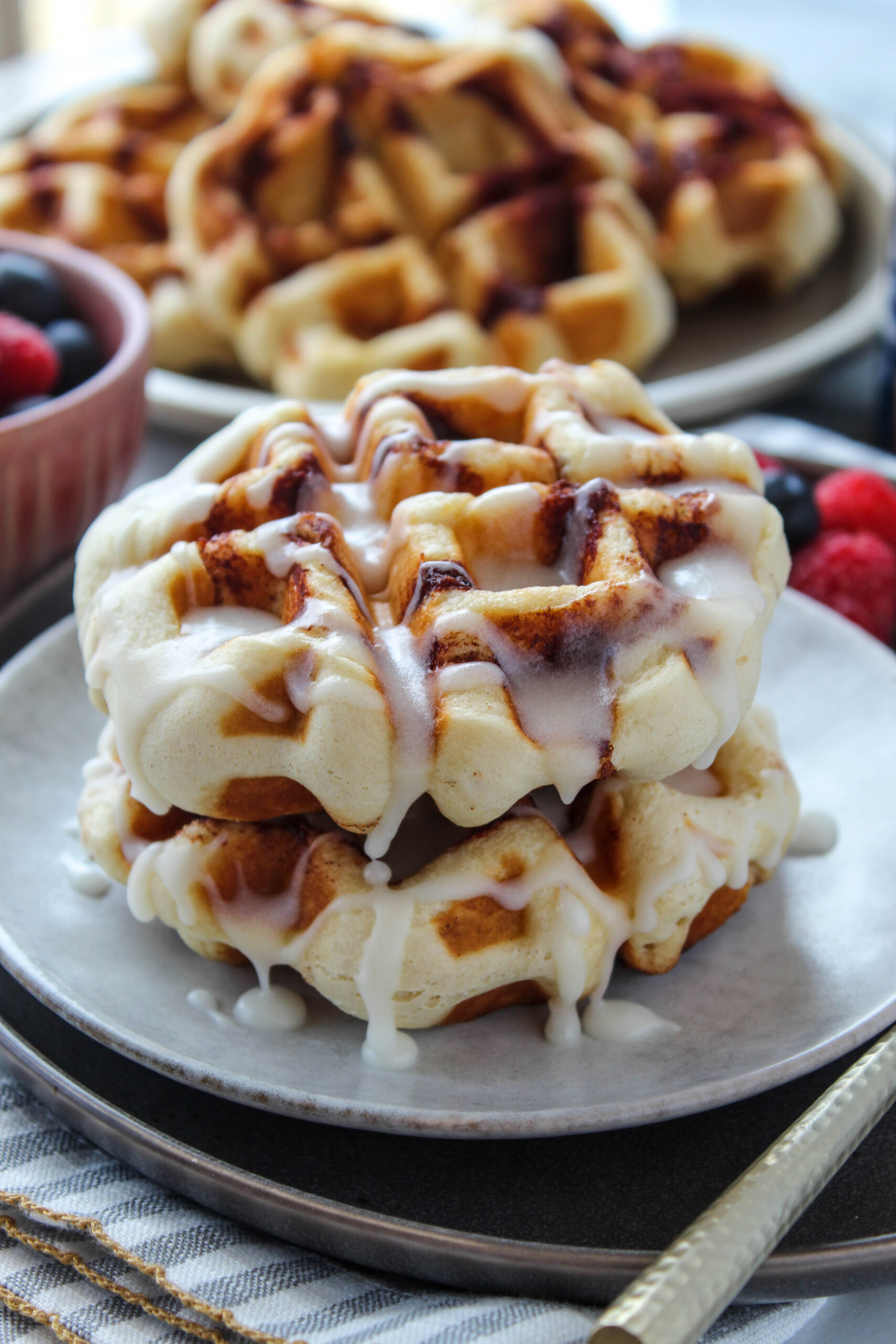 Cinnamon roll waffles served with fresh fruit and a drizzle of icing