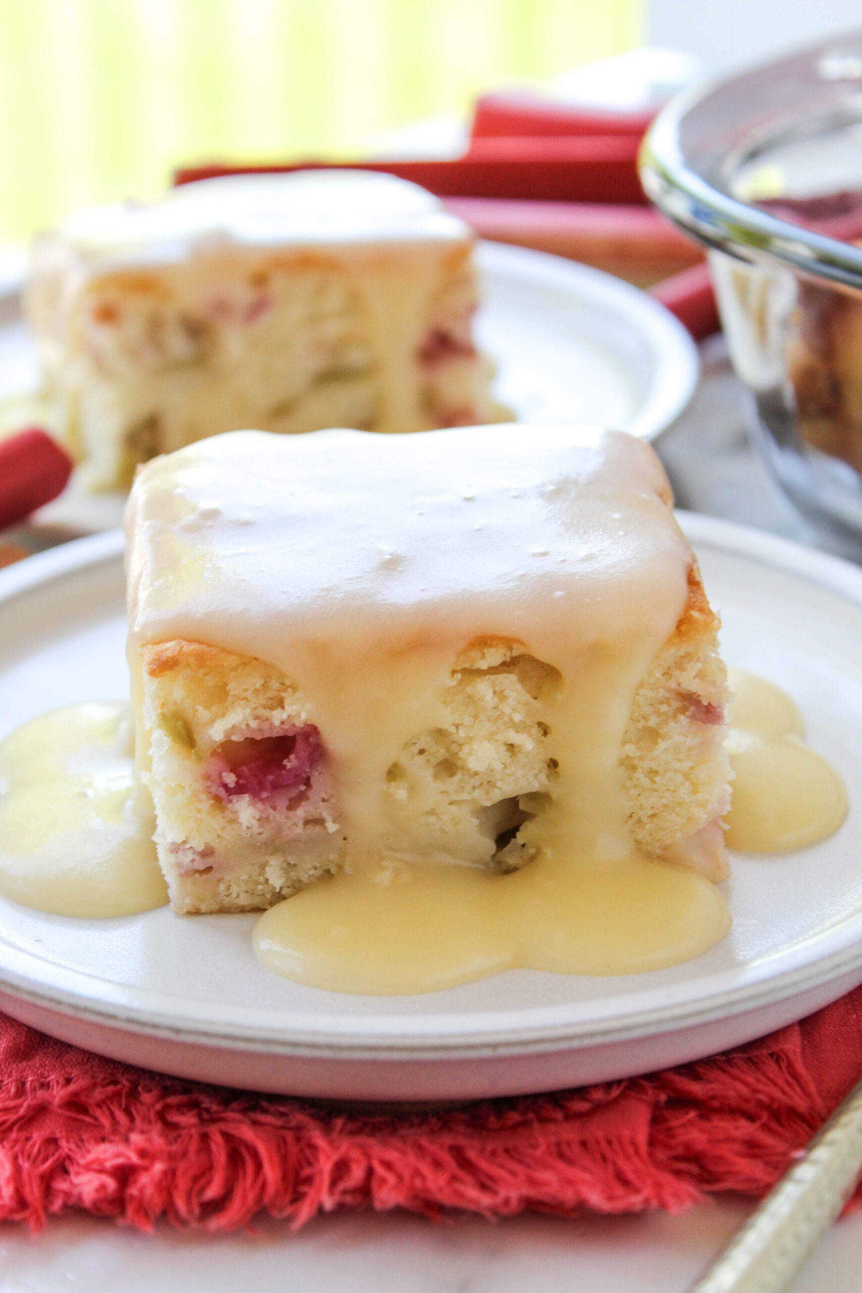 Slice of rhubarb cake topped with warm butter sauce on a plate