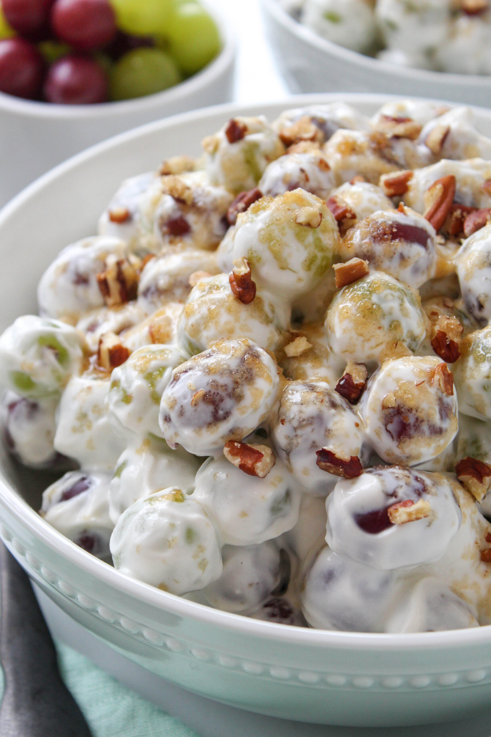 Creamy grape salad with red and green grapes topped with brown sugar and chopped pecans
