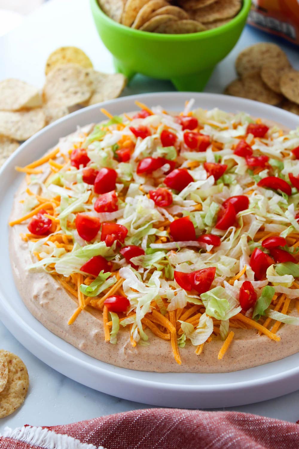 The best taco dip recipe layered with cream cheese, seasoned taco filling, lettuce, tomatoes, and cheese