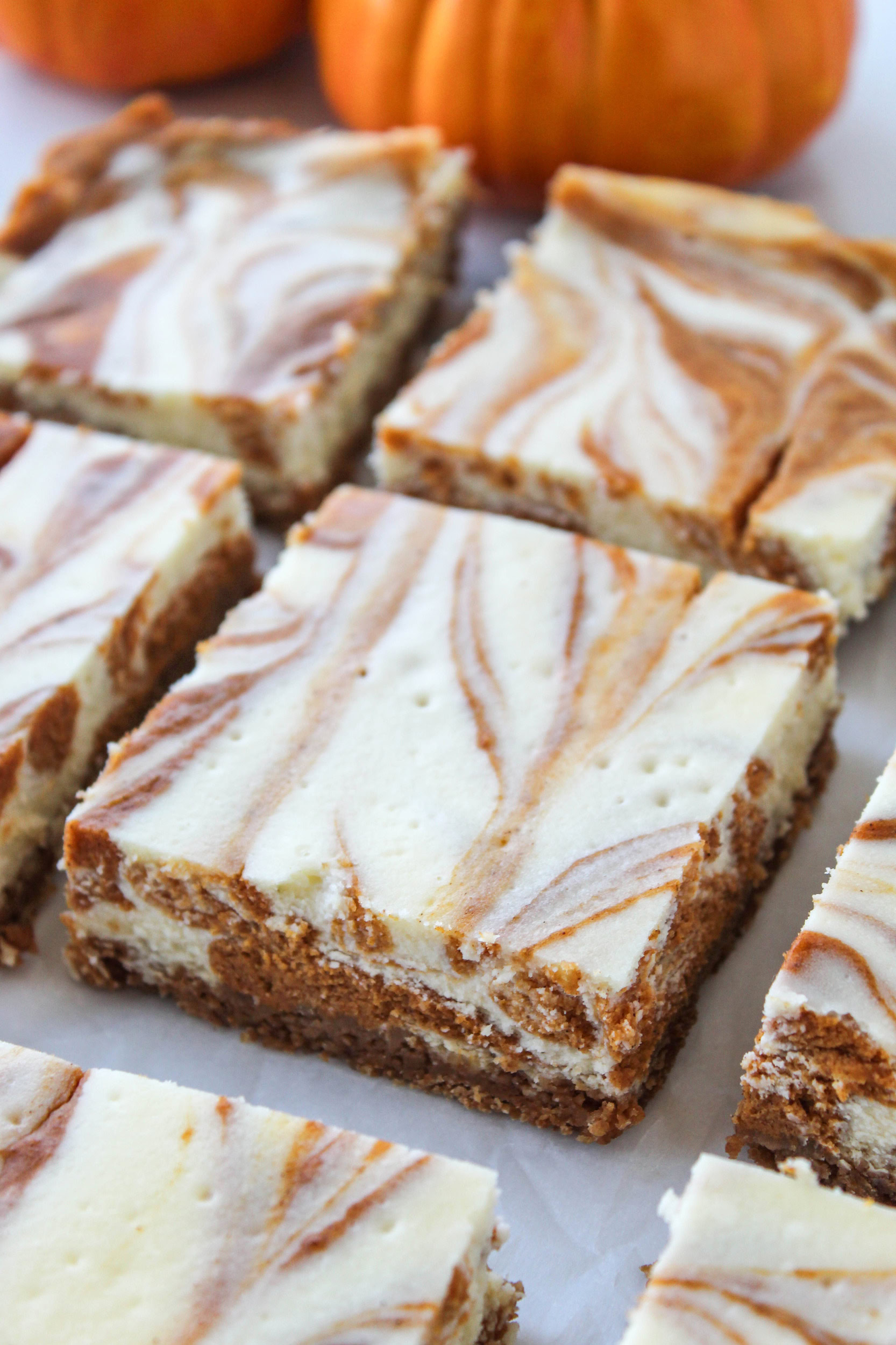 Swirled pumpkin cheesecake bars with a marbled pumpkin and cream cheese top on a graham cracker crust