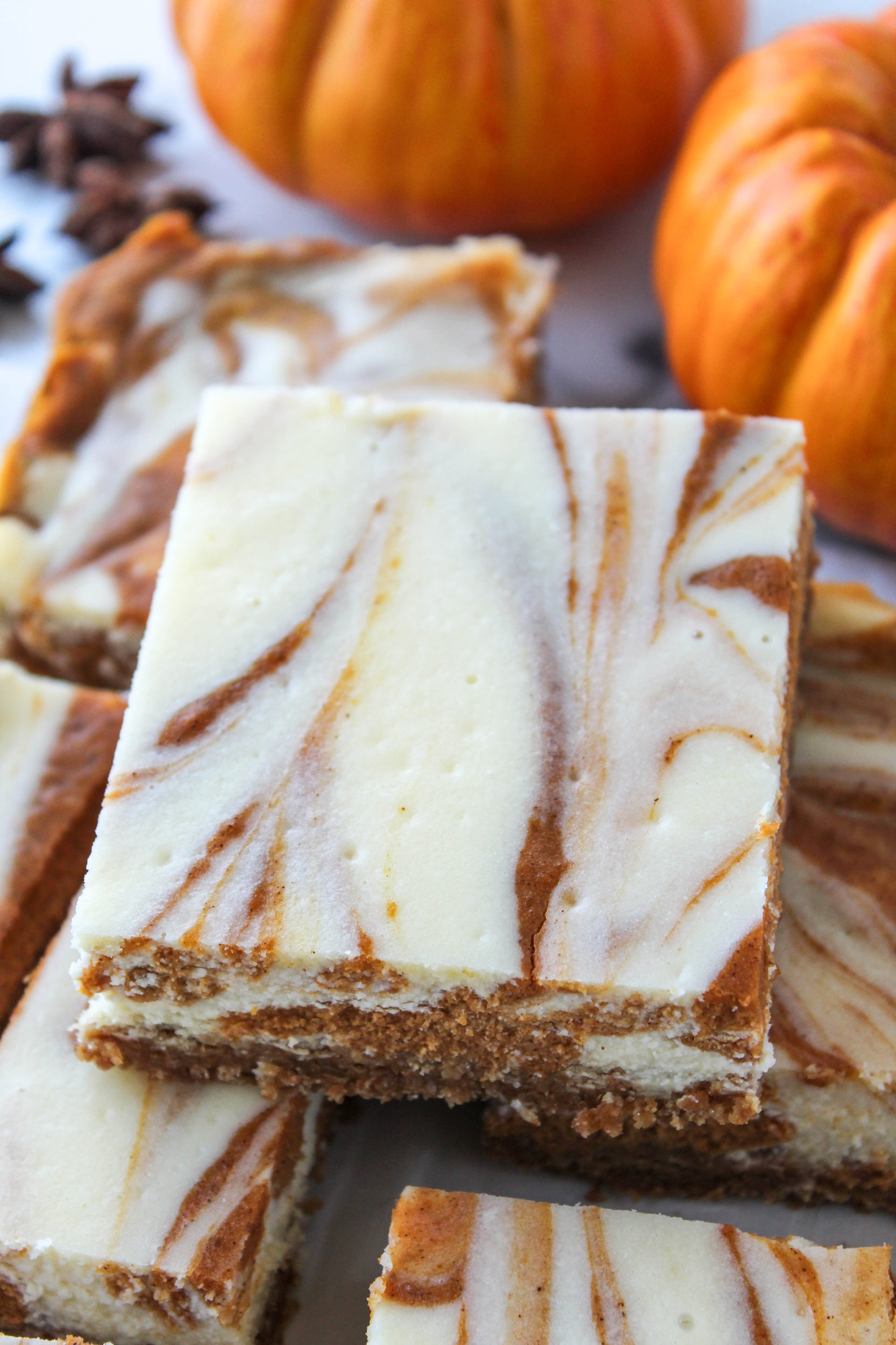 Pumpkin cheesecake bars cut into squares and arranged on parchment paper