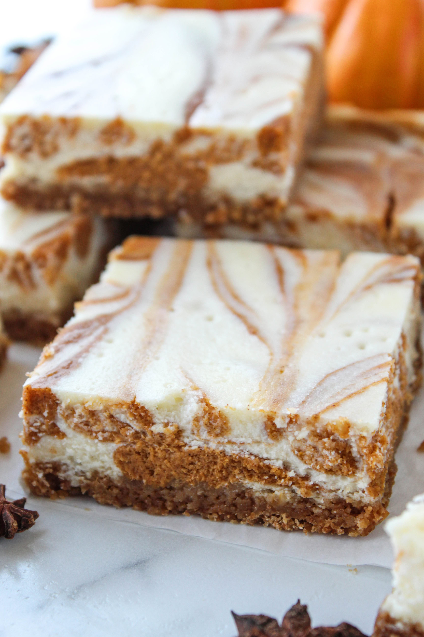 A slice of swirled pumpkin cheesecake bar with visible creamy layers and graham crust