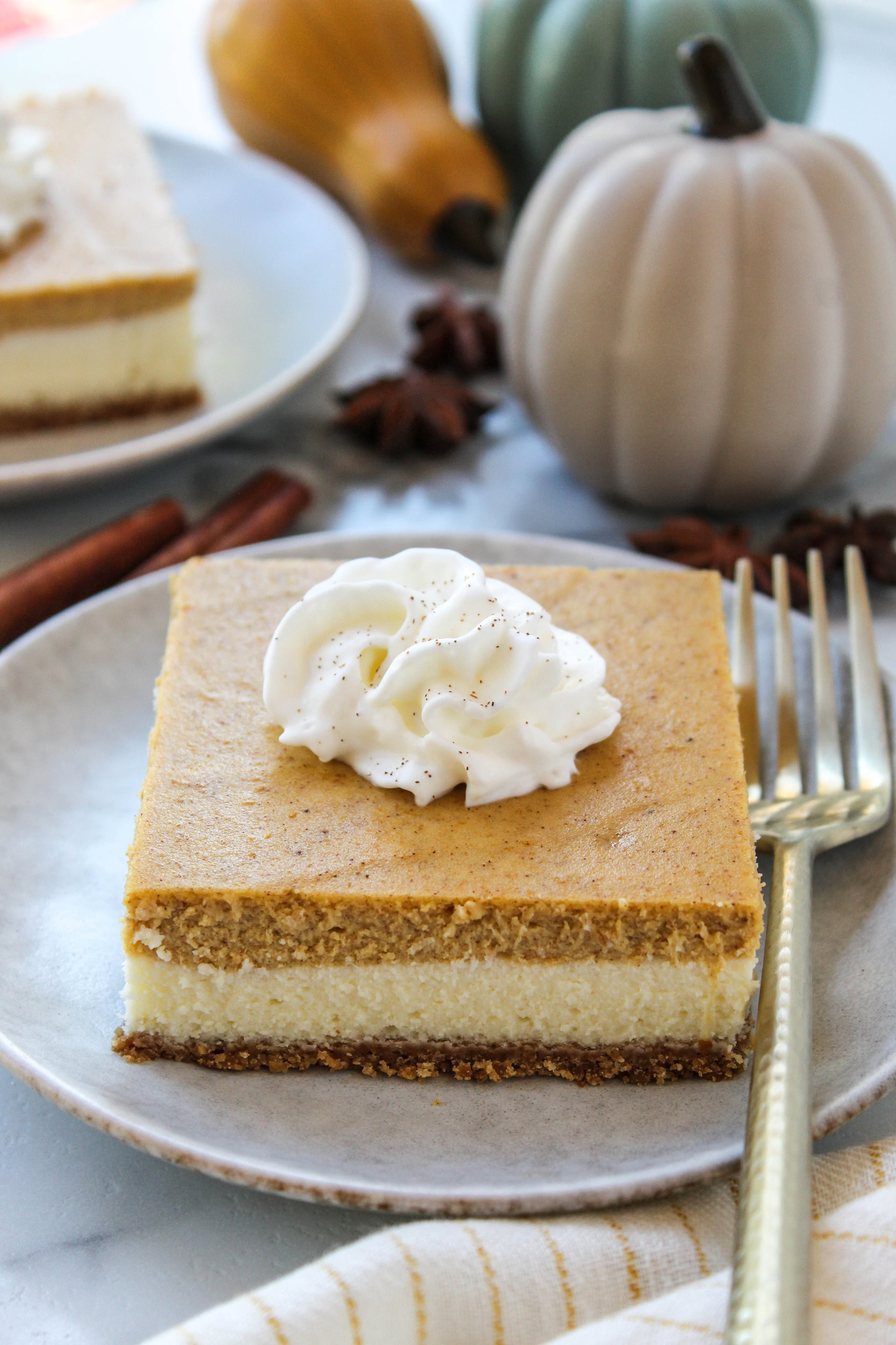 Pumpkin cheesecake dessert bars topped with a sprinkle of cinnamon