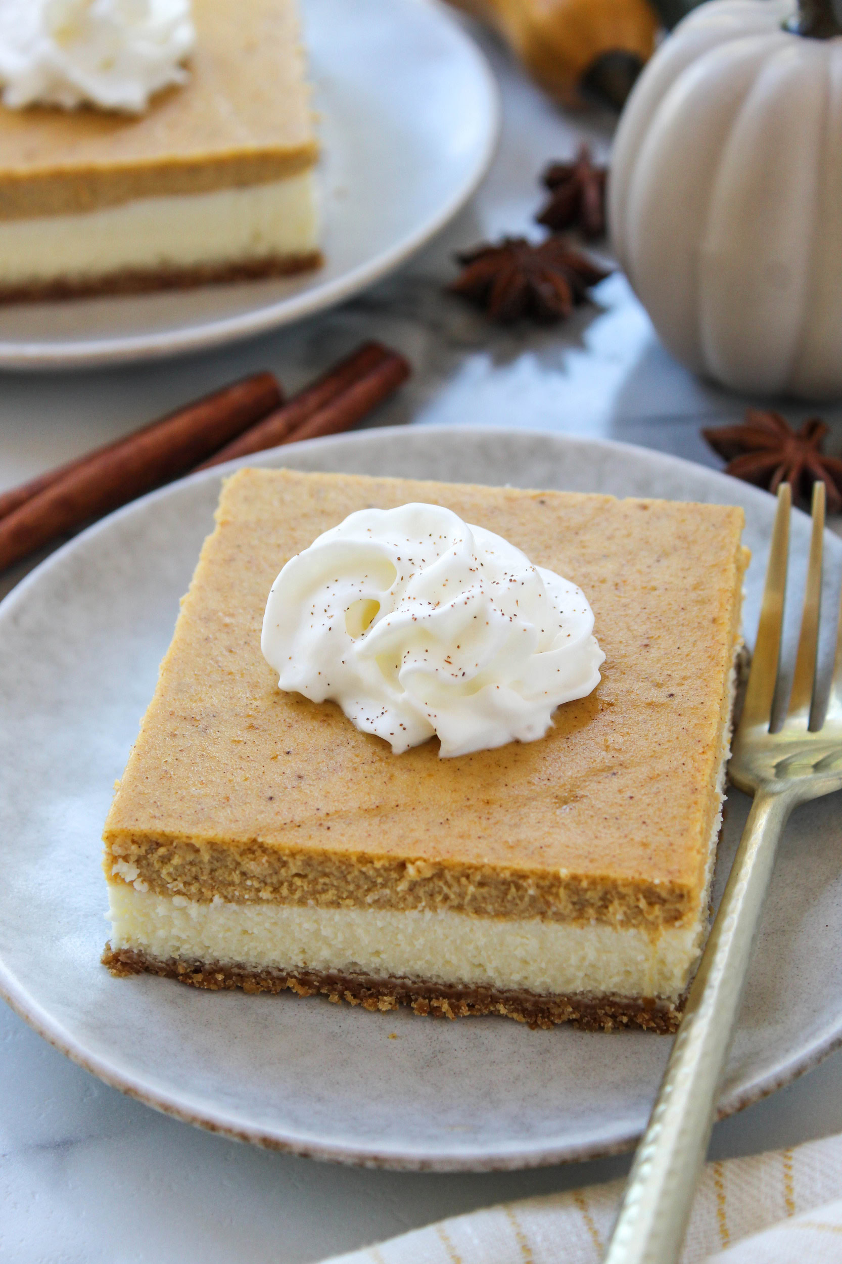 Homemade pumpkin cheesecake bars sliced into squares on a serving plate