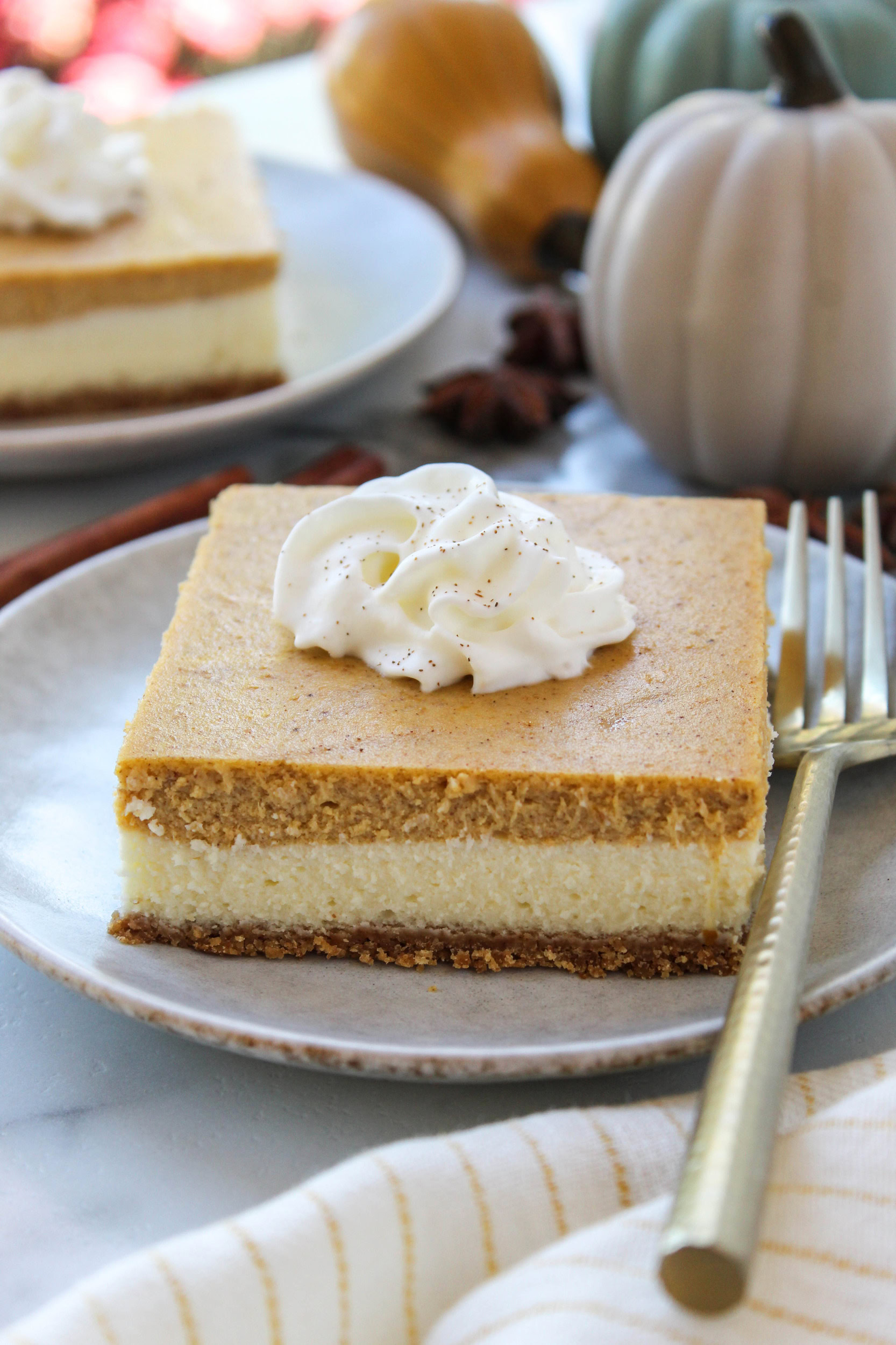 Pumpkin cheesecake bars with a creamy cheesecake layer and pumpkin spice filling