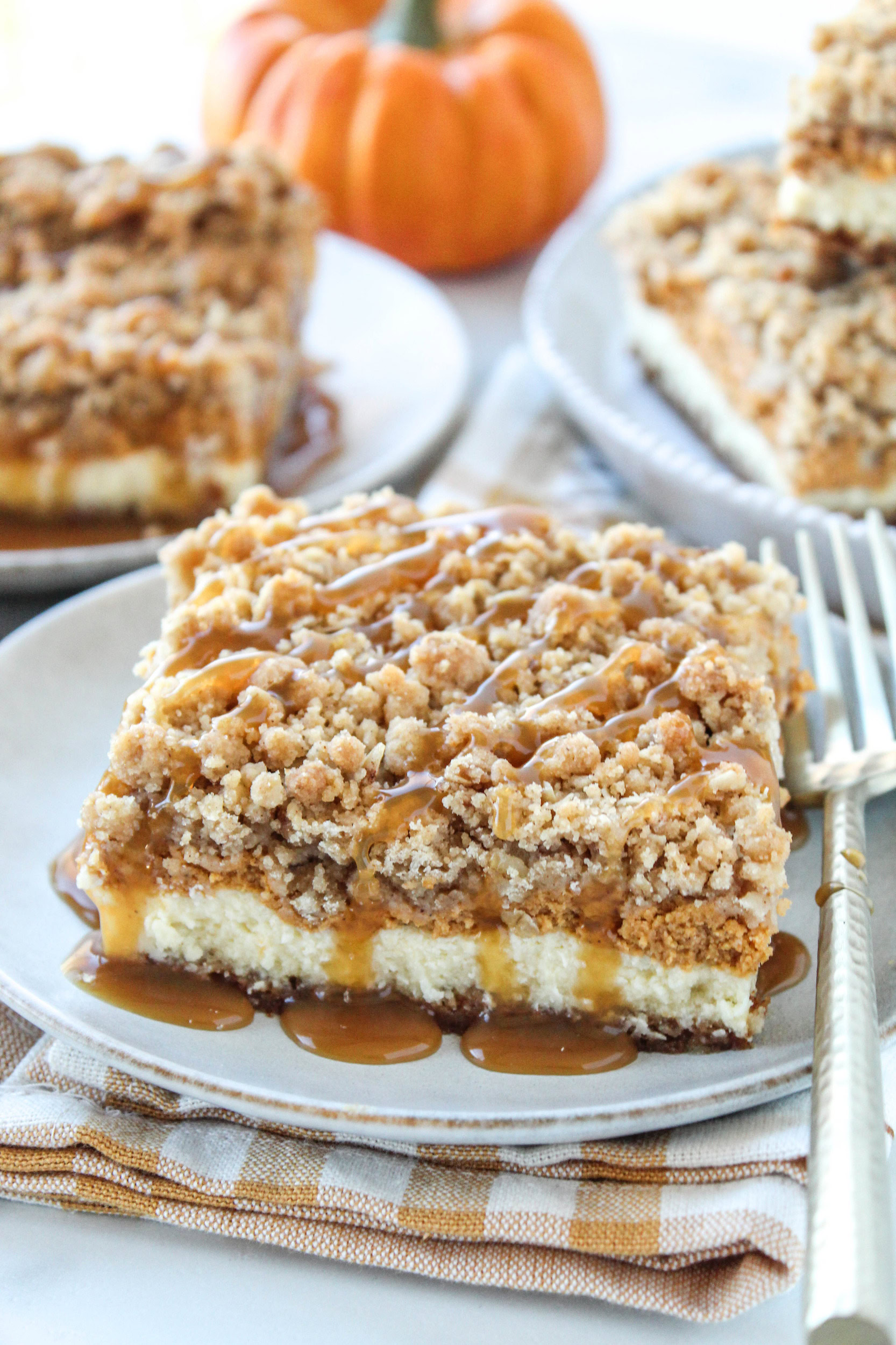 Pumpkin caramel cheesecake bars topped with a rich caramel drizzle