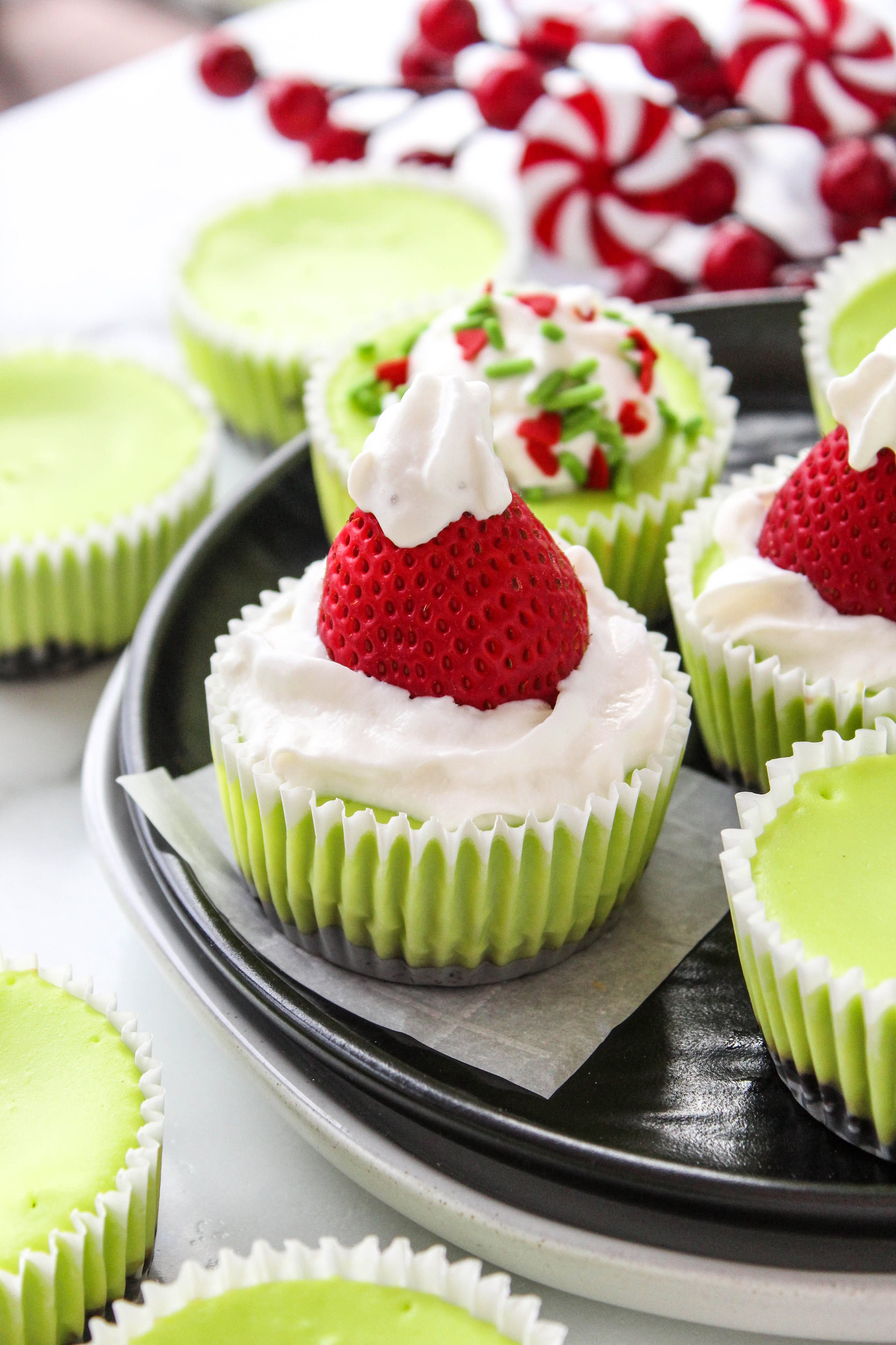 Close-up of Grinch-themed mini cheesecakes on a holiday dessert tray
