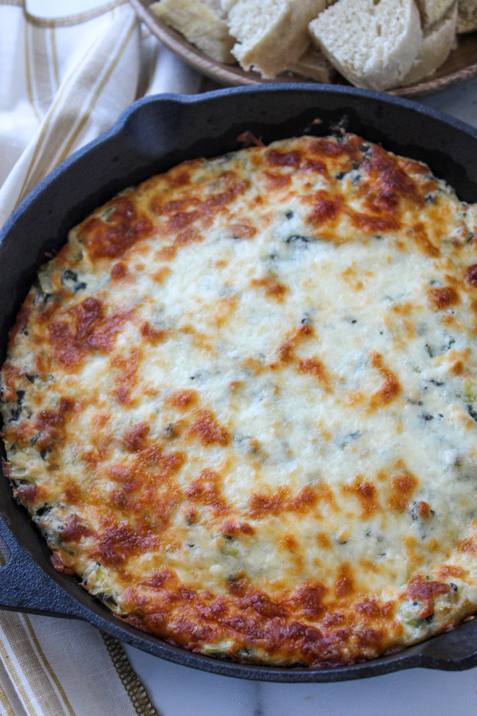 Overhead shot of cheesy spinach artichoke dip with golden top