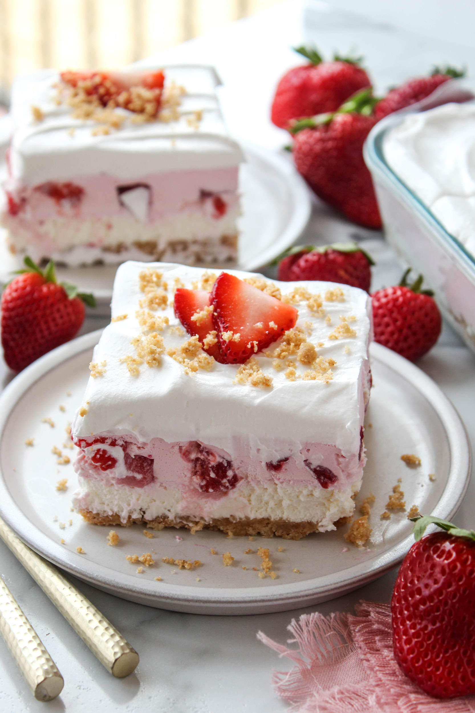 Strawberry lasagna dessert with layers of cream cheese, whipped topping, and fresh strawberries