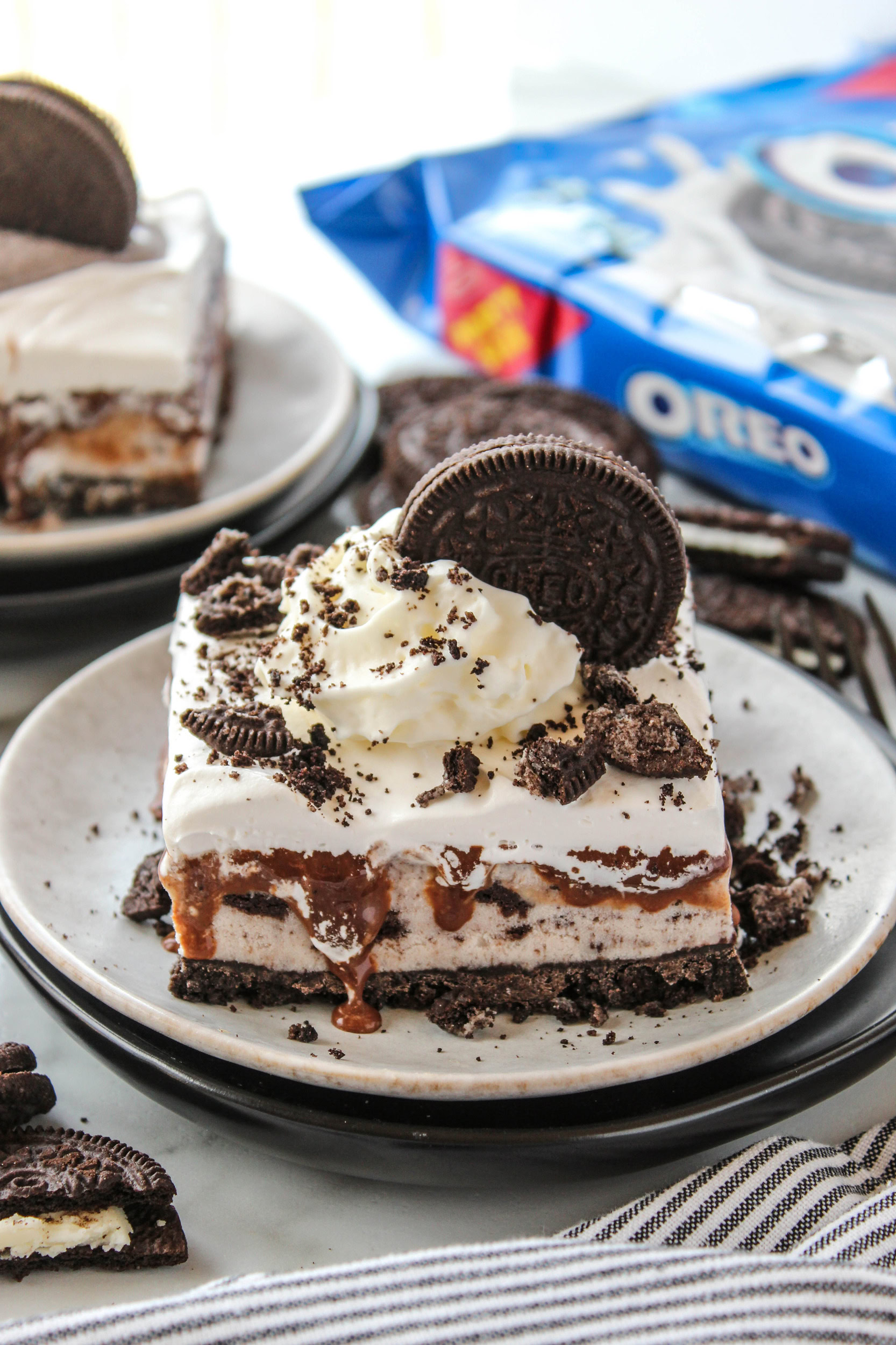 Layered Oreo ice cream cake with a chocolate cookie crust, hot fudge filling, and whipped topping