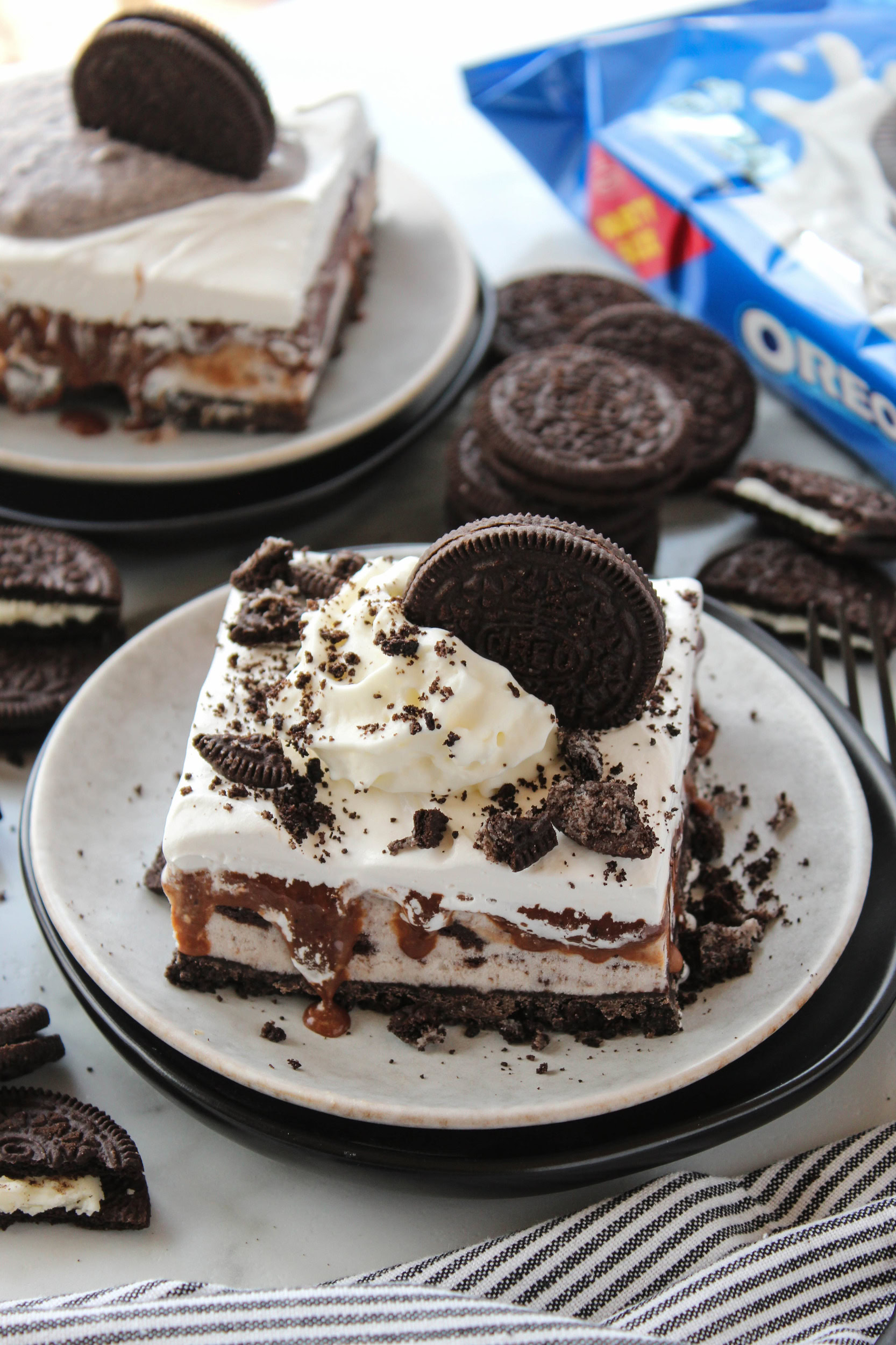 Slice of Oreo ice cream cake showing layers of chocolate cookie crust, creamy ice cream, and rich fudge