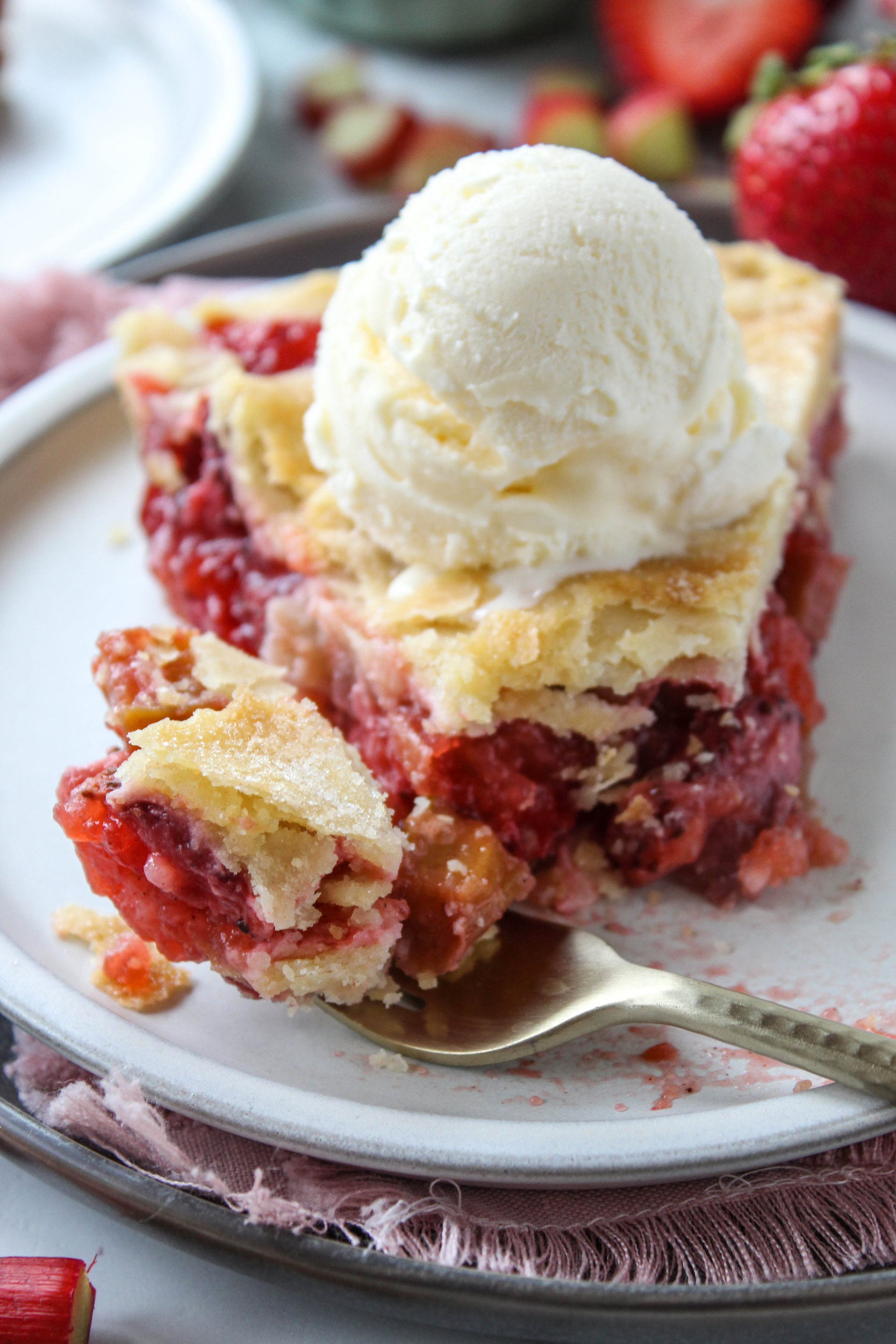 Slice of strawberry rhubarb pie served with vanilla ice cream