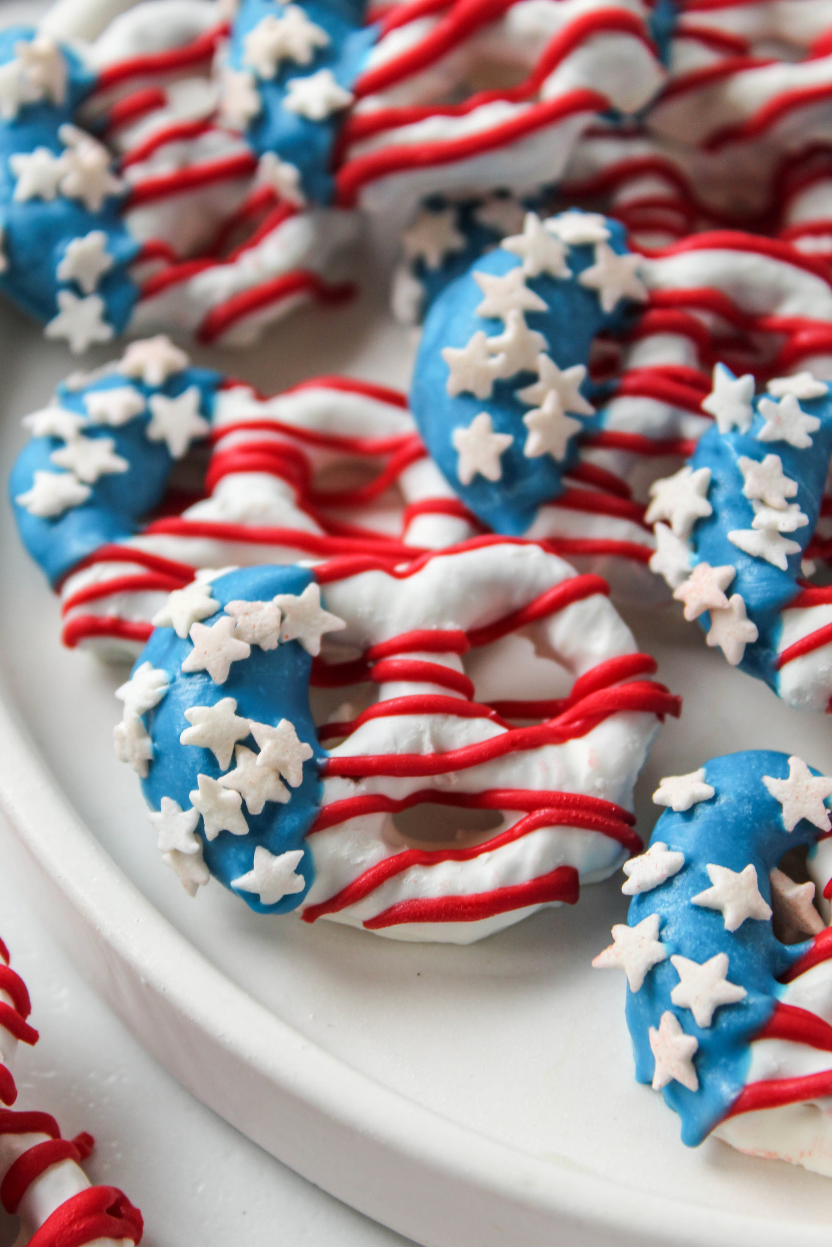 4th of July flag pretzels decorated with red, white, and blue candy melts and star sprinkles