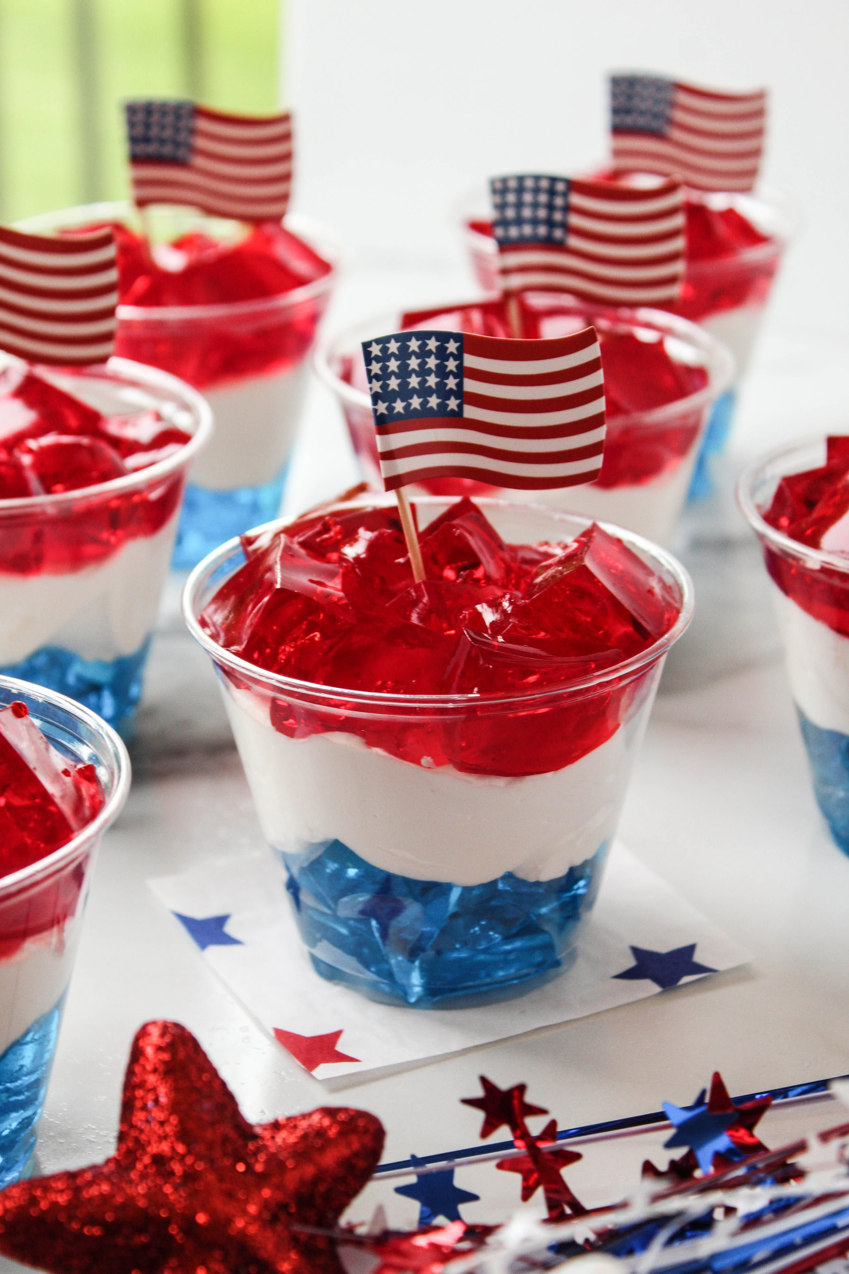 Clear plastic cups filled with layered red, white, and blue Jell‑O for a patriotic dessert