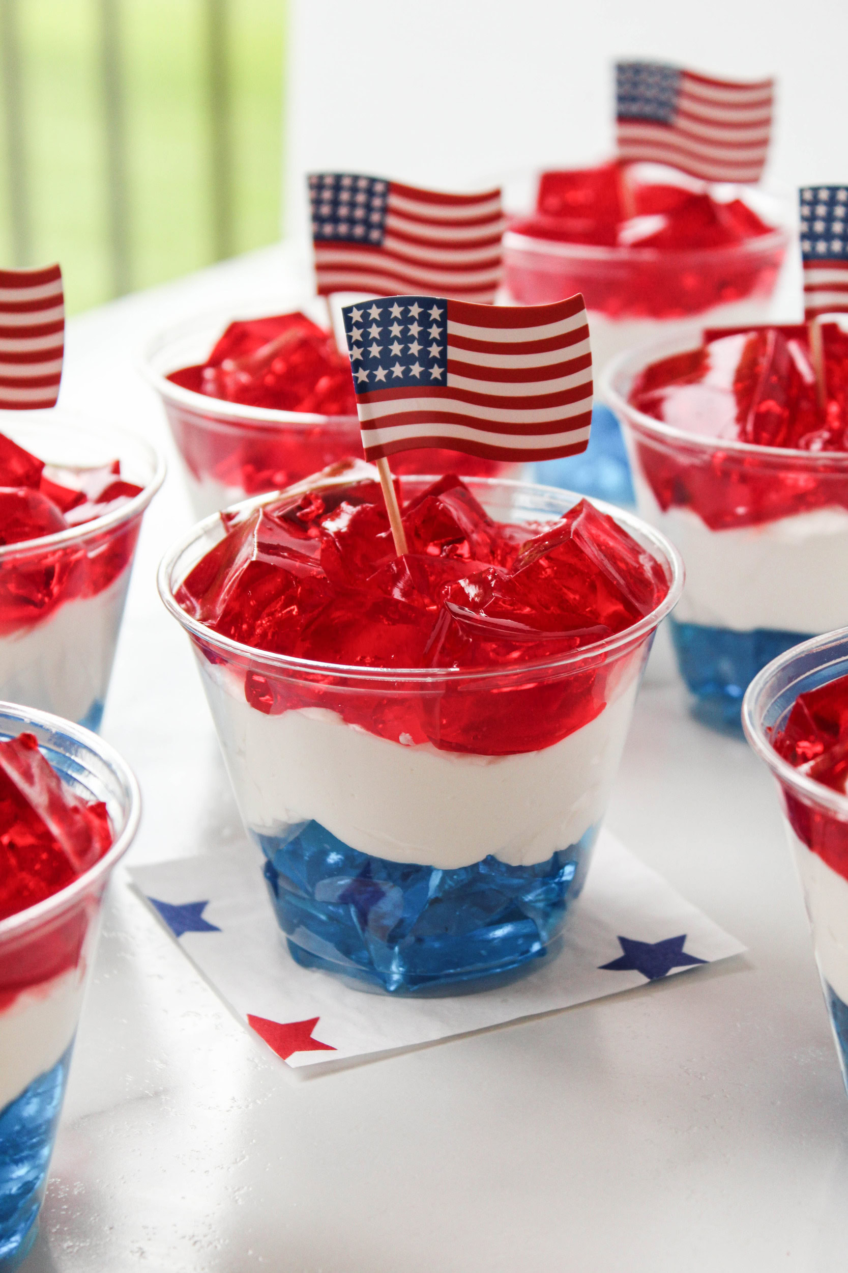 Festive red, white, and blue Jell‑O cups with distinct layered colors, served in clear cups for a patriotic theme