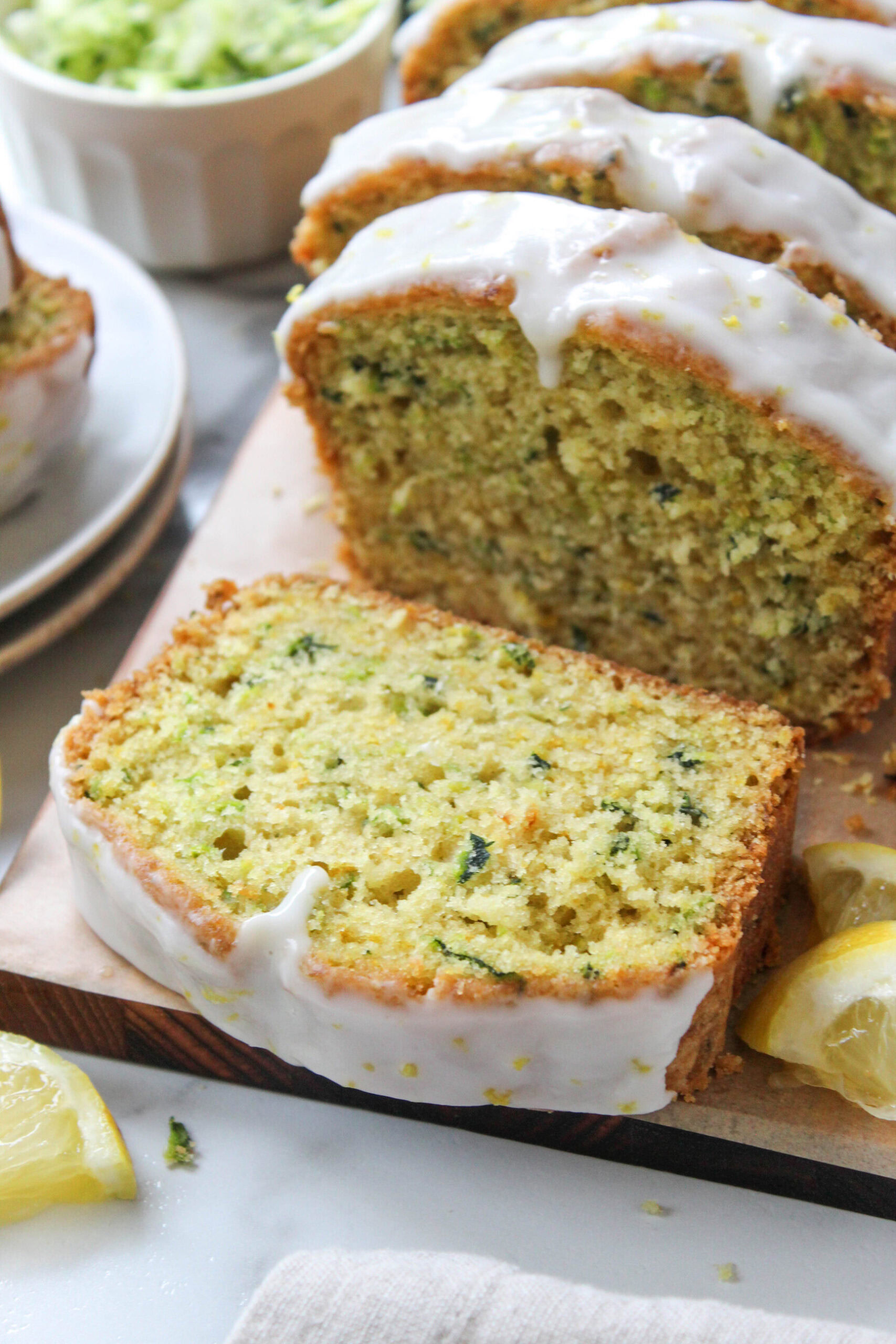 Freshly baked lemon zucchini loaf covered in a smooth lemon glaze and sliced for serving