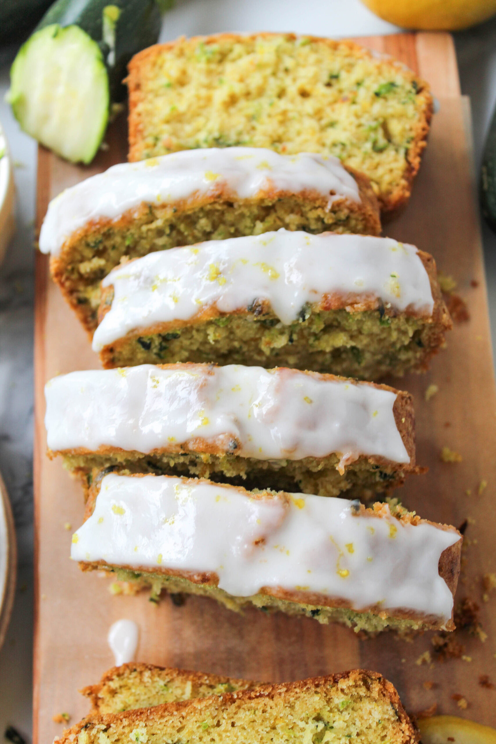 Lemon zucchini bread loaf topped with a glossy glaze and scattered lemon zest
