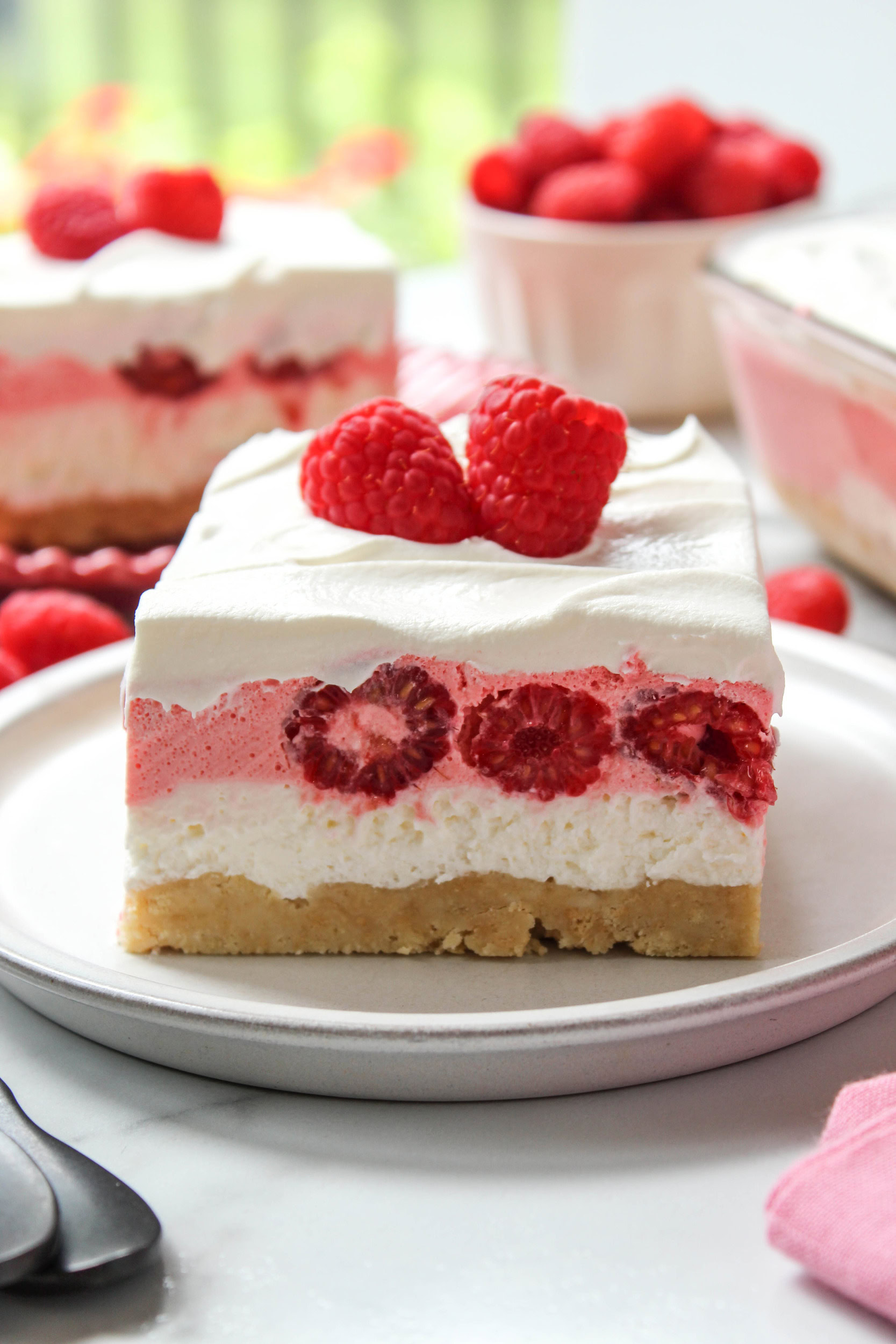 Slice of raspberry lasagna topped with whipped cream and fresh berries