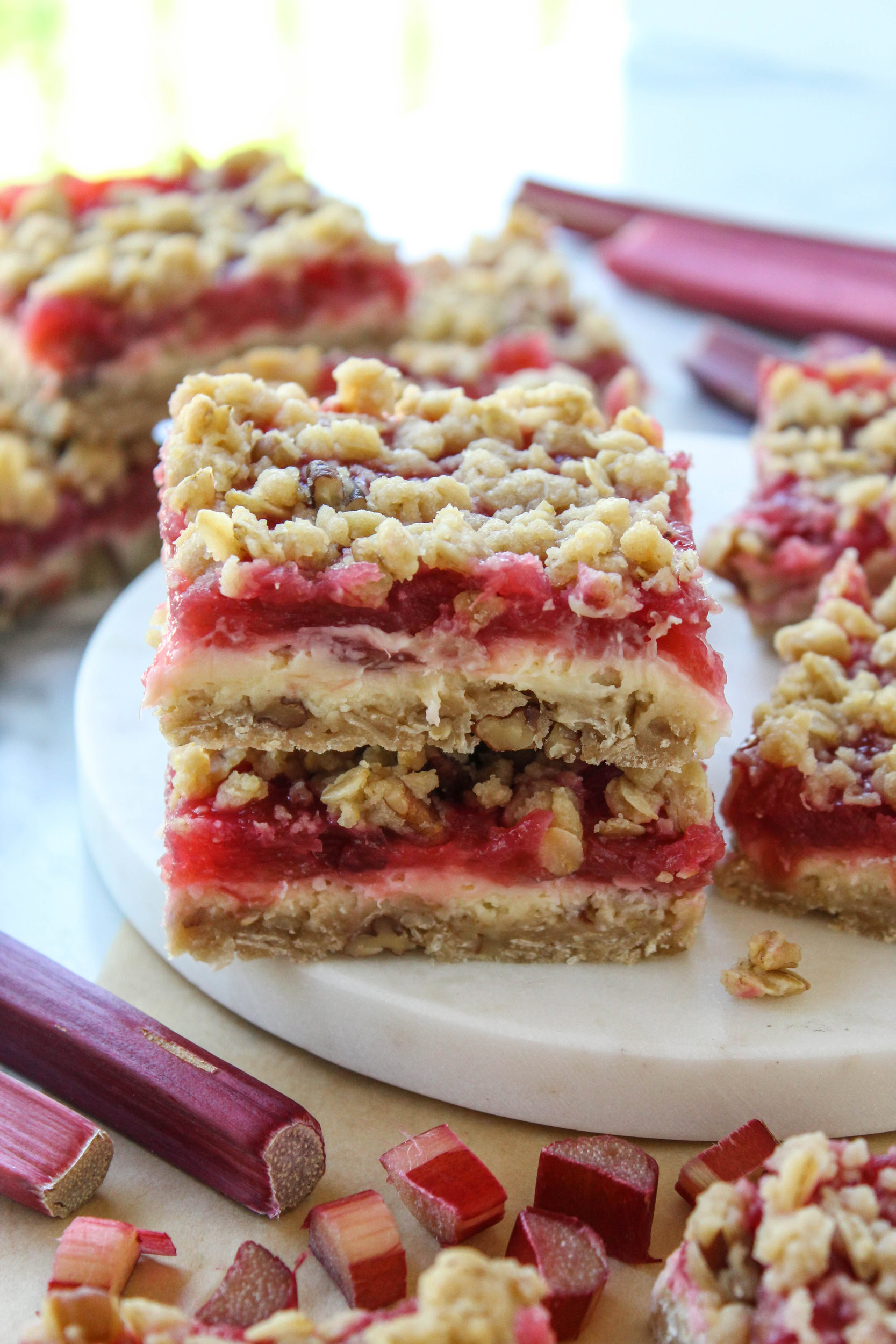Stack of rhubarb cheesecake bars showing layered crust, cheesecake filling, and glossy rhubarb topping