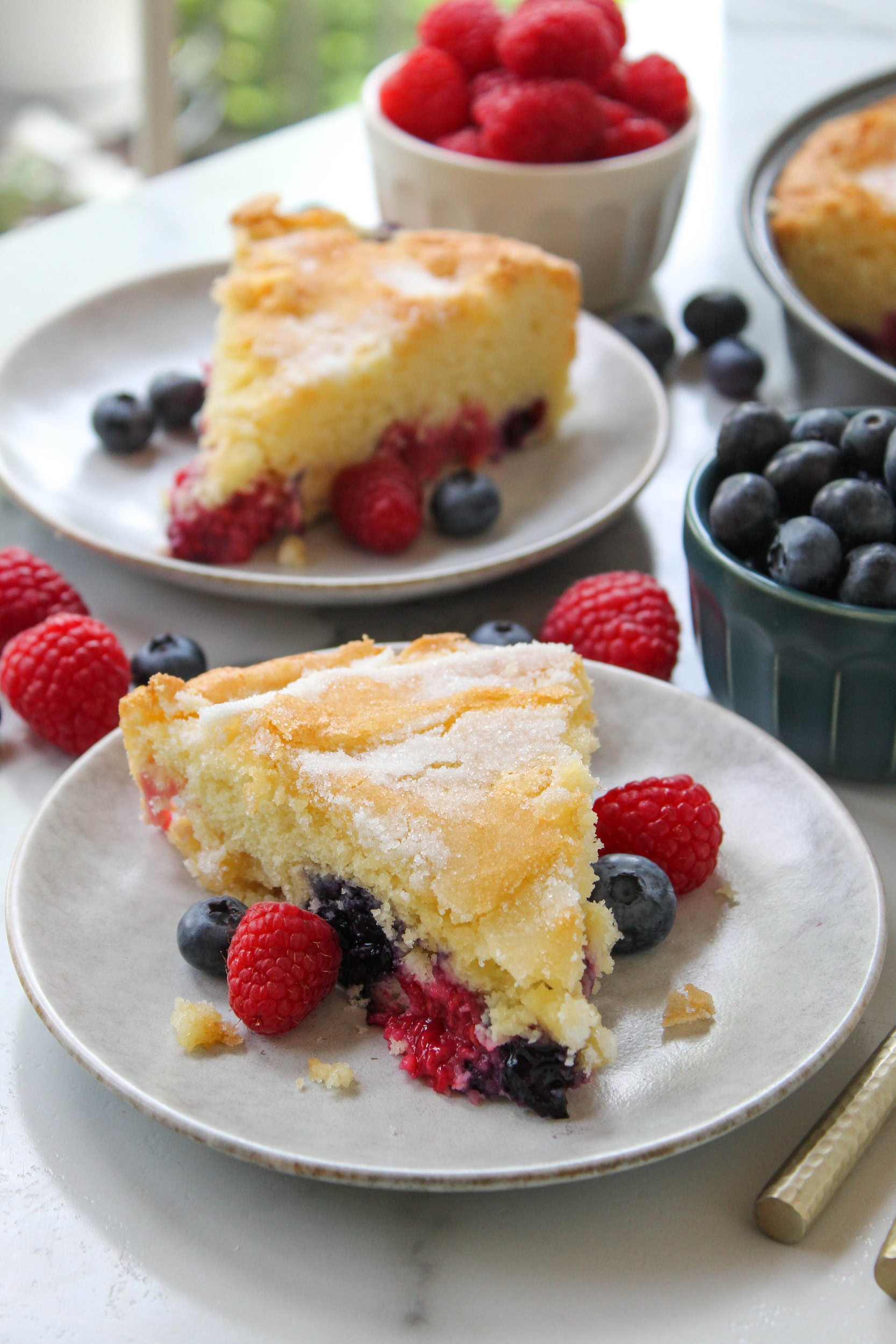 slice of mixed berry cake with fresh raspberries and blueberries