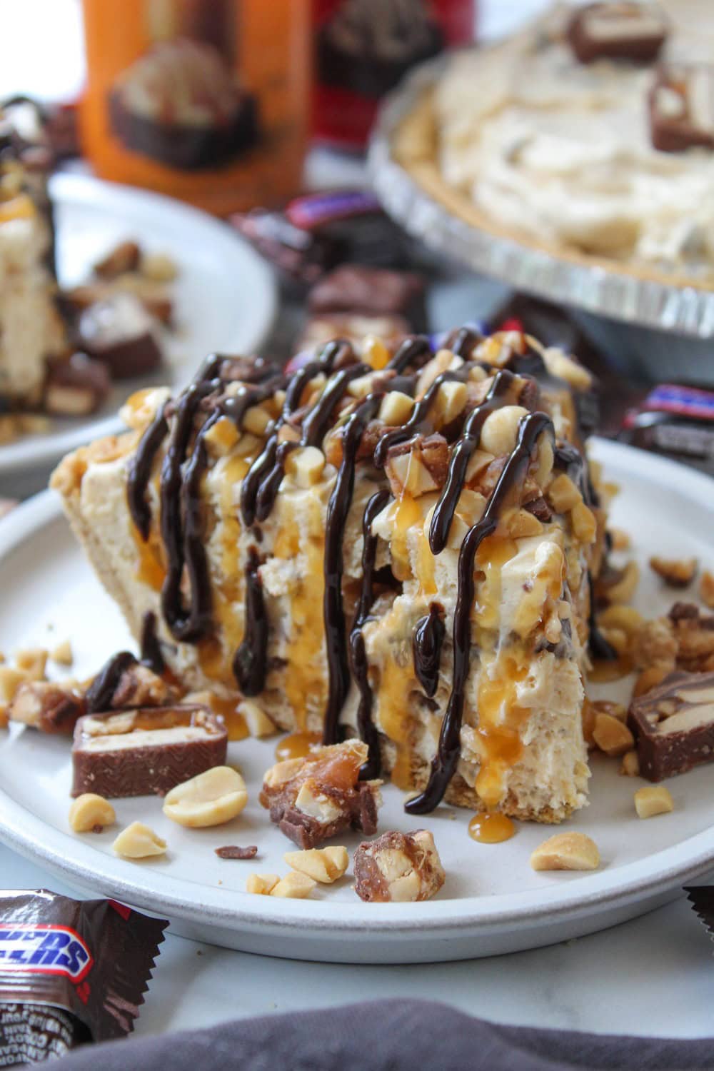 Creamy no-bake Snickers pie in a graham cracker crust, garnished with candy pieces and caramel sauce