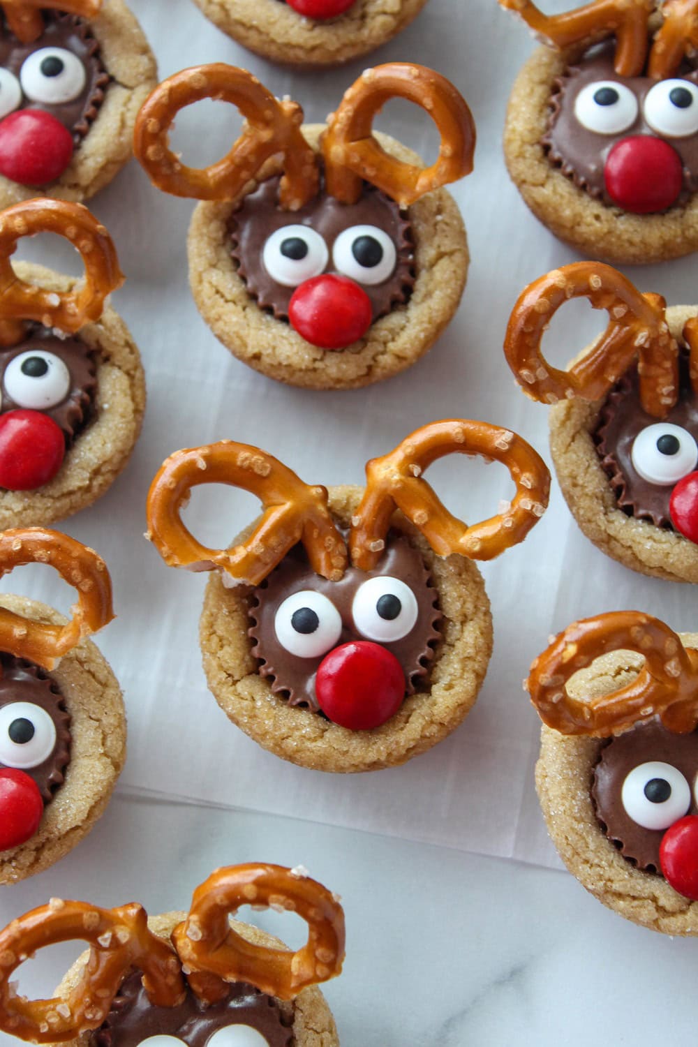 Peanut butter cookies topped with Reese’s cups decorated like reindeer faces
