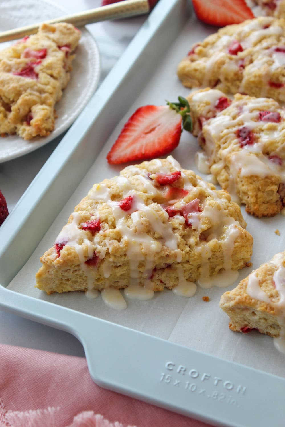 Strawberry lemon scones topped with lemon glaze on a baking sheet