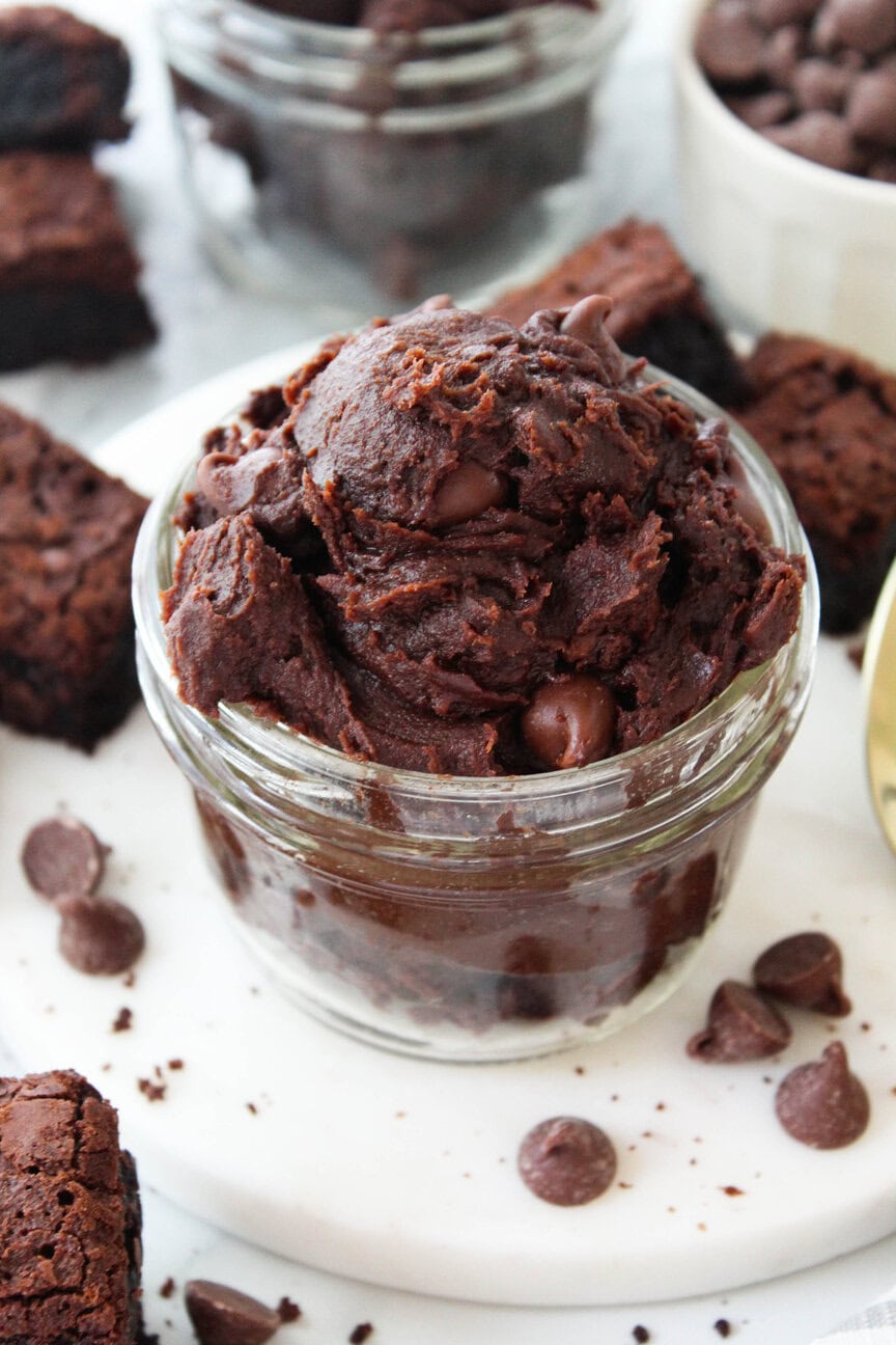 Edible brownie batter served in a small bowl with a spoon beside it